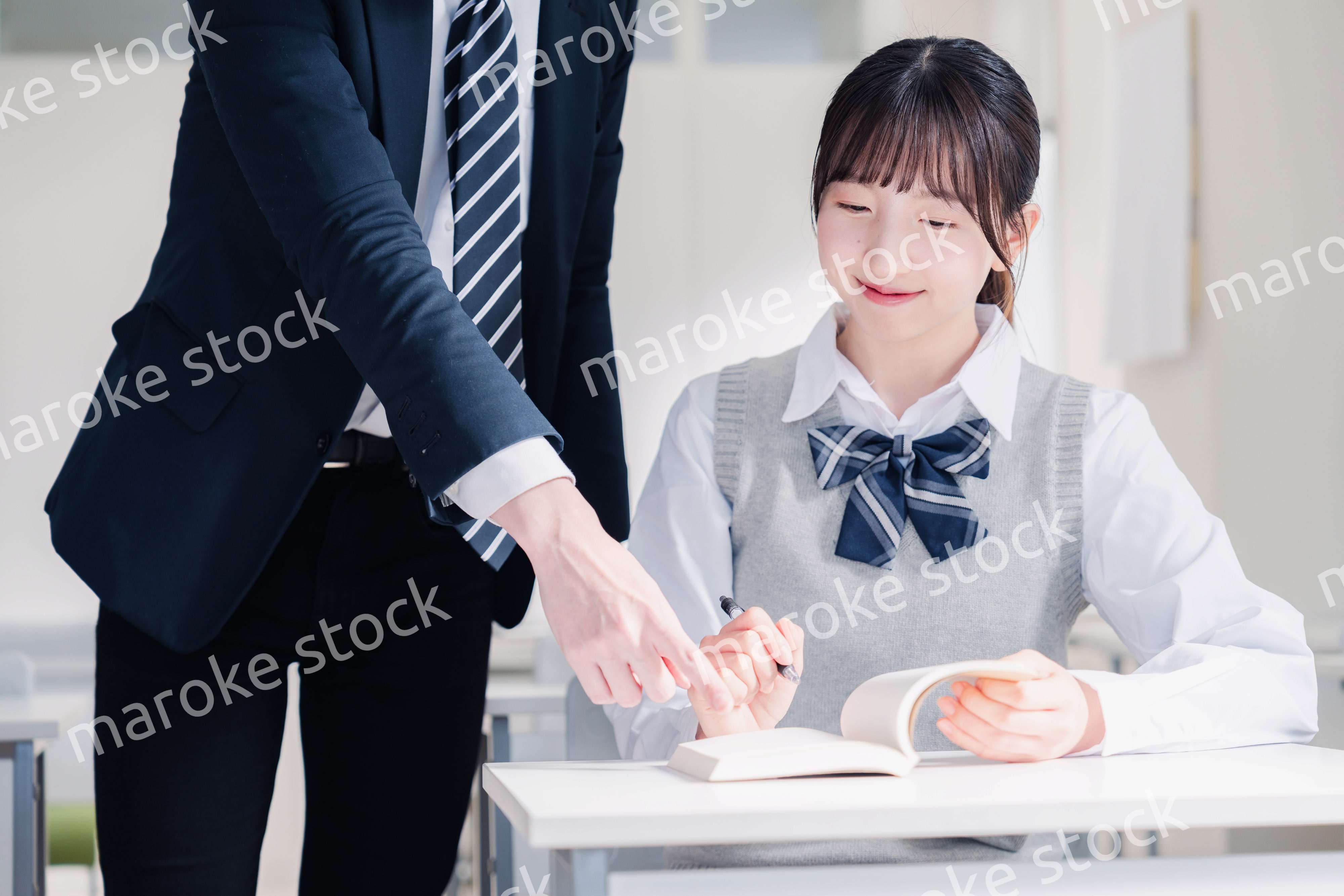 教室で先生に質問をする女子高生