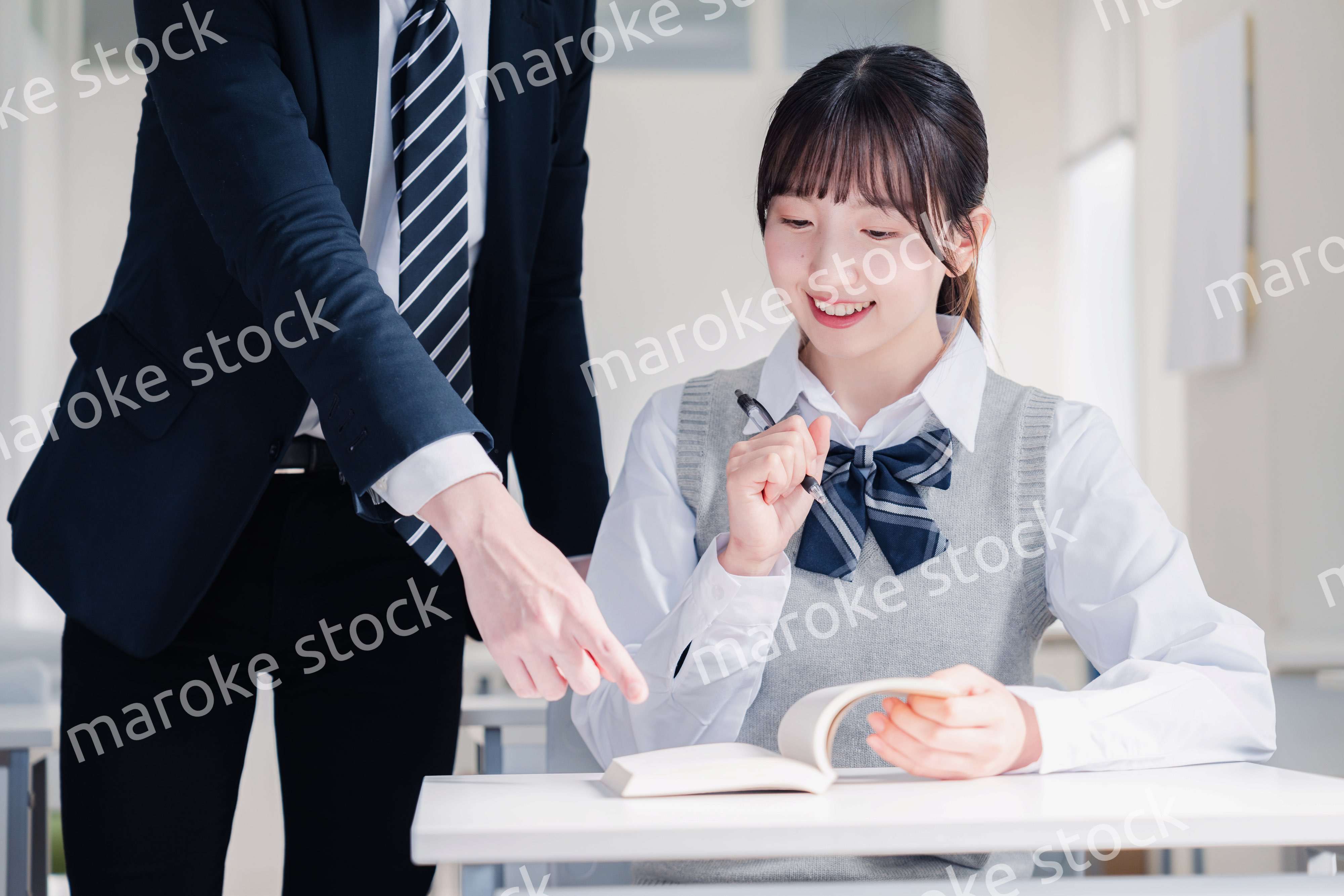 教室で先生に質問をする女子高生