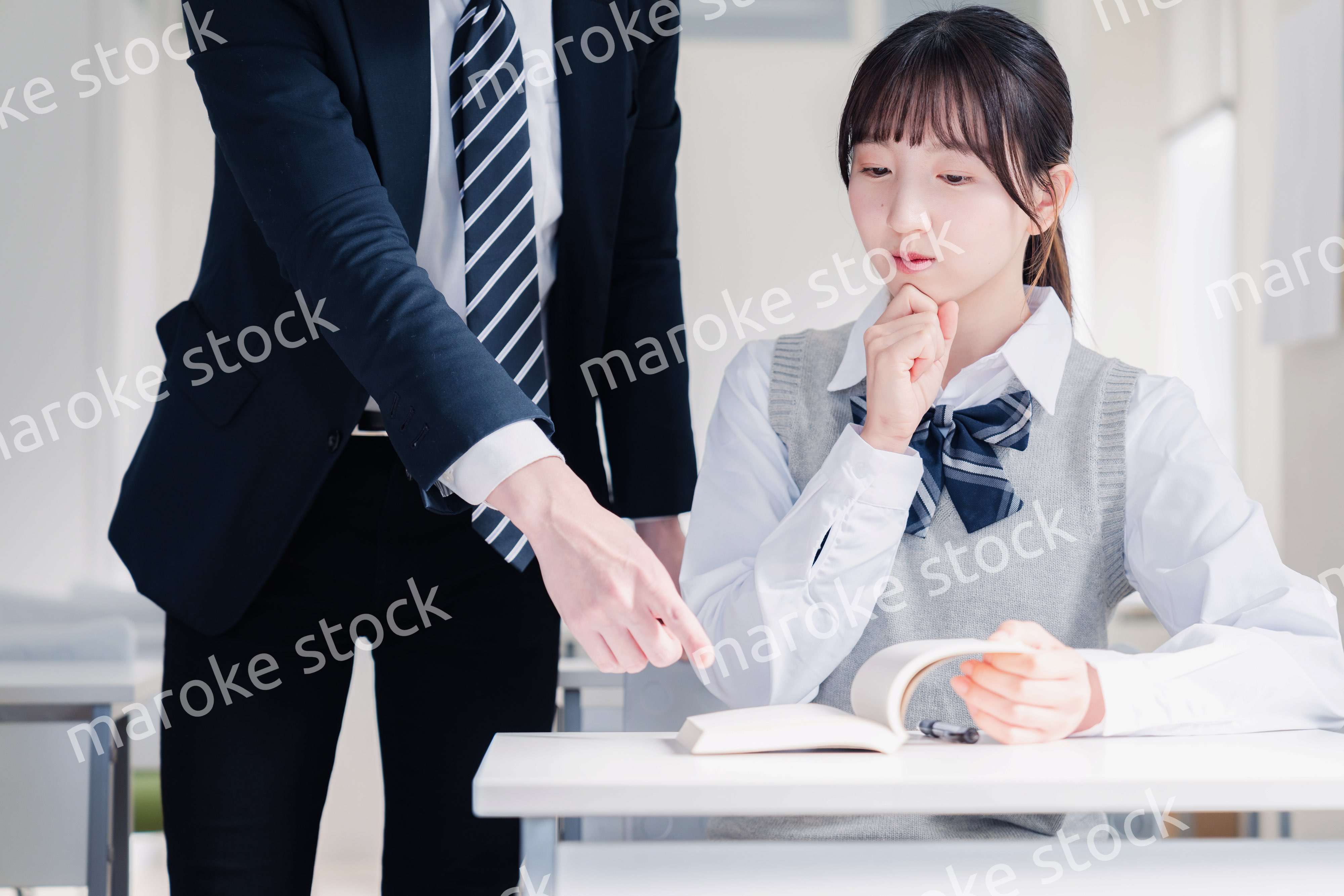 教室で先生に質問をする女子高生