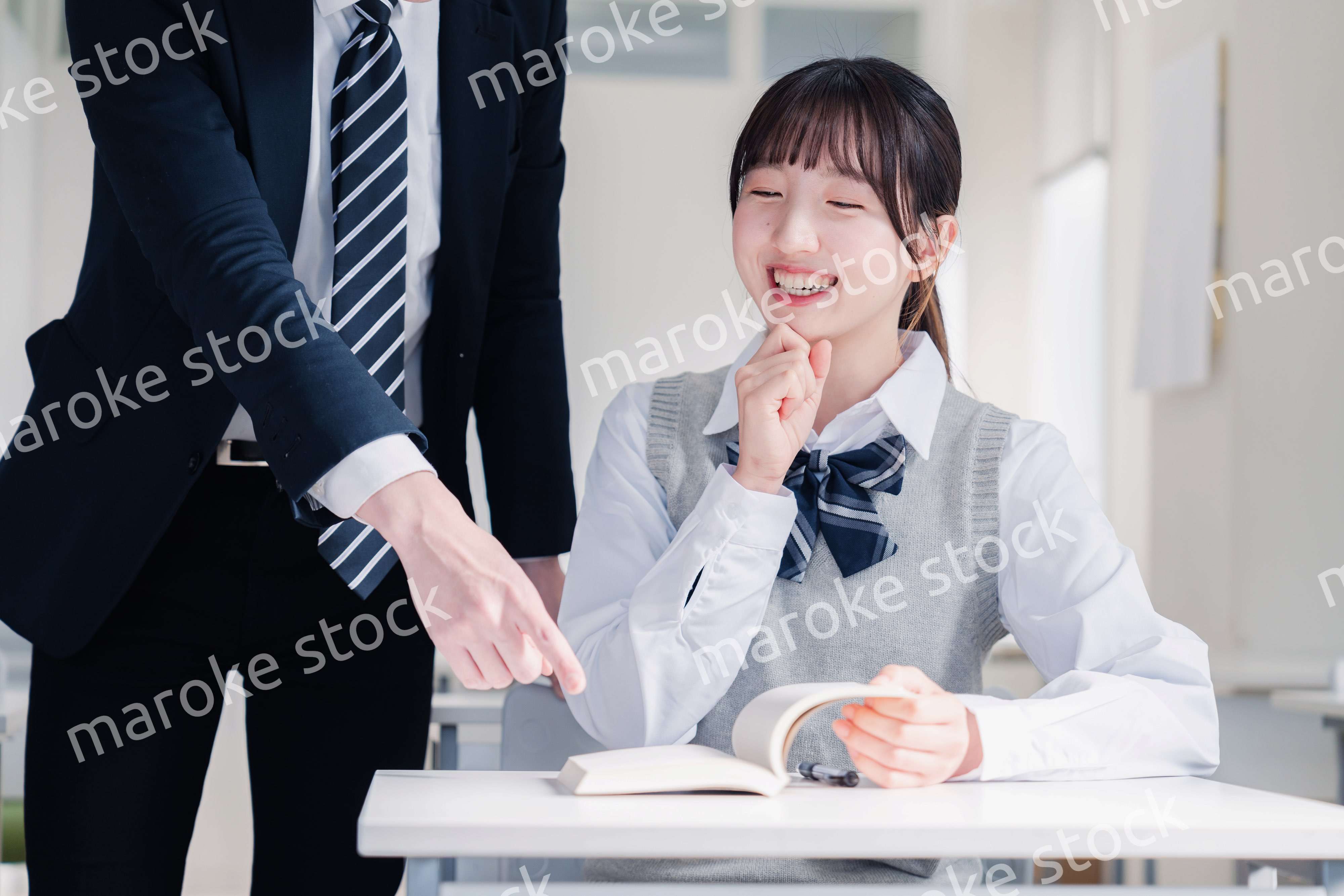 教室で先生に質問をする女子高生