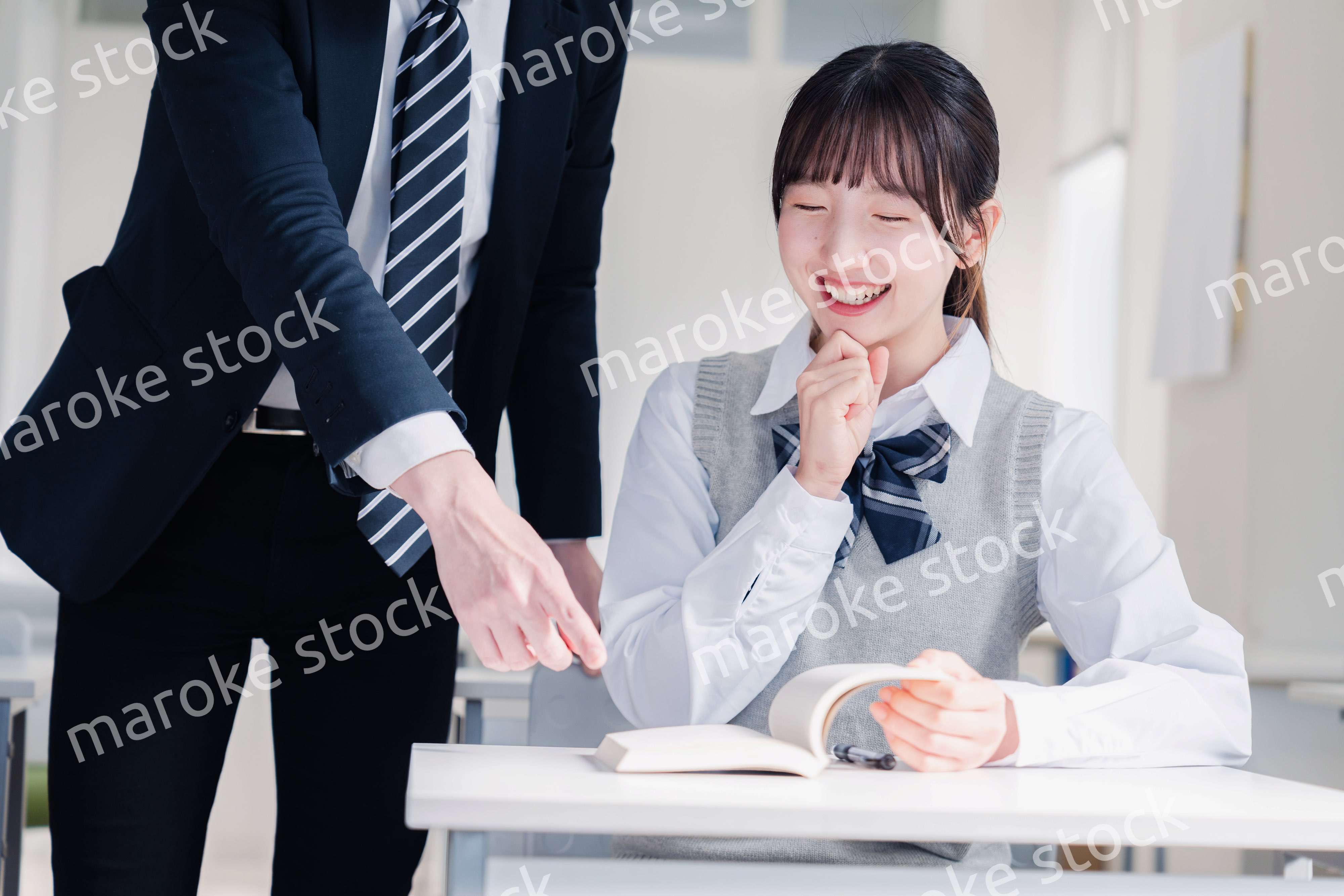 教室で先生に質問をする女子高生