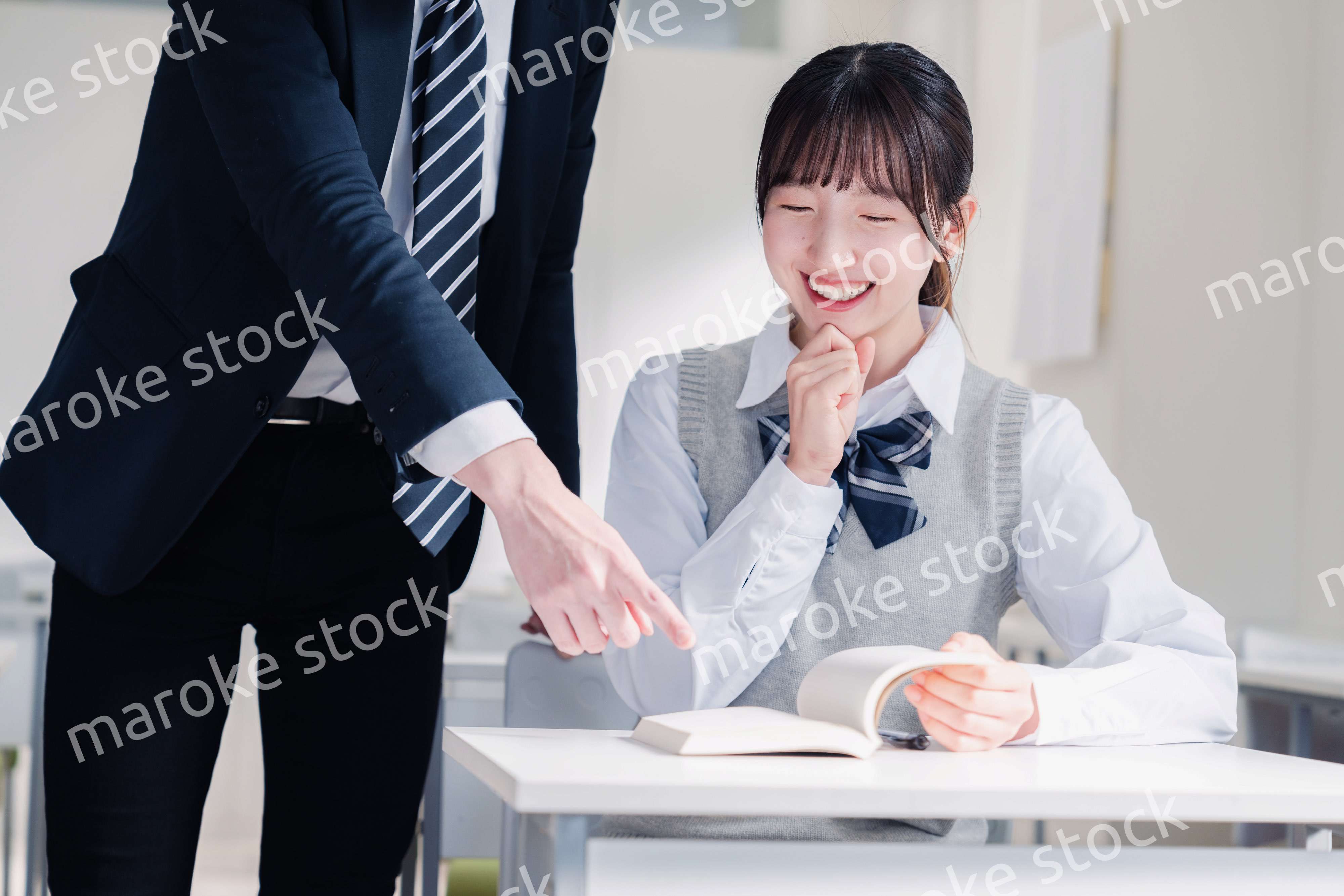 教室で先生に質問をする女子高生