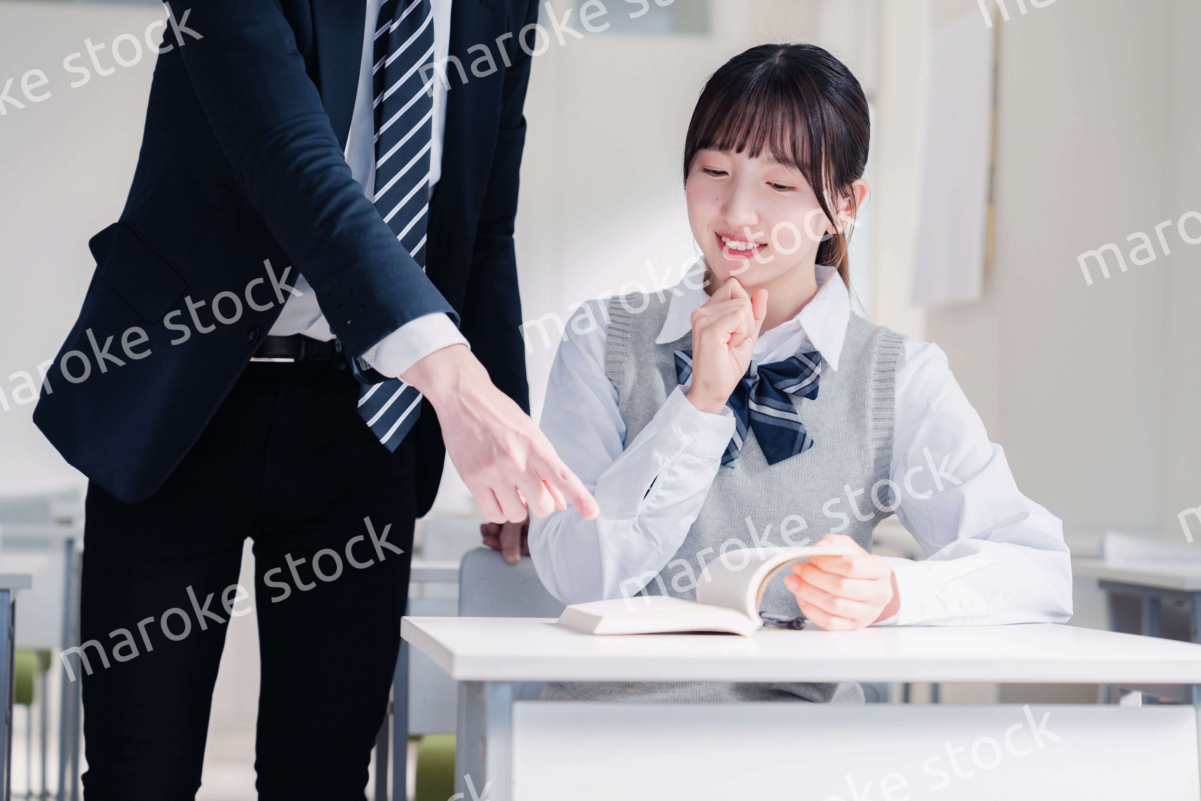 教室で先生に質問をする女子高生