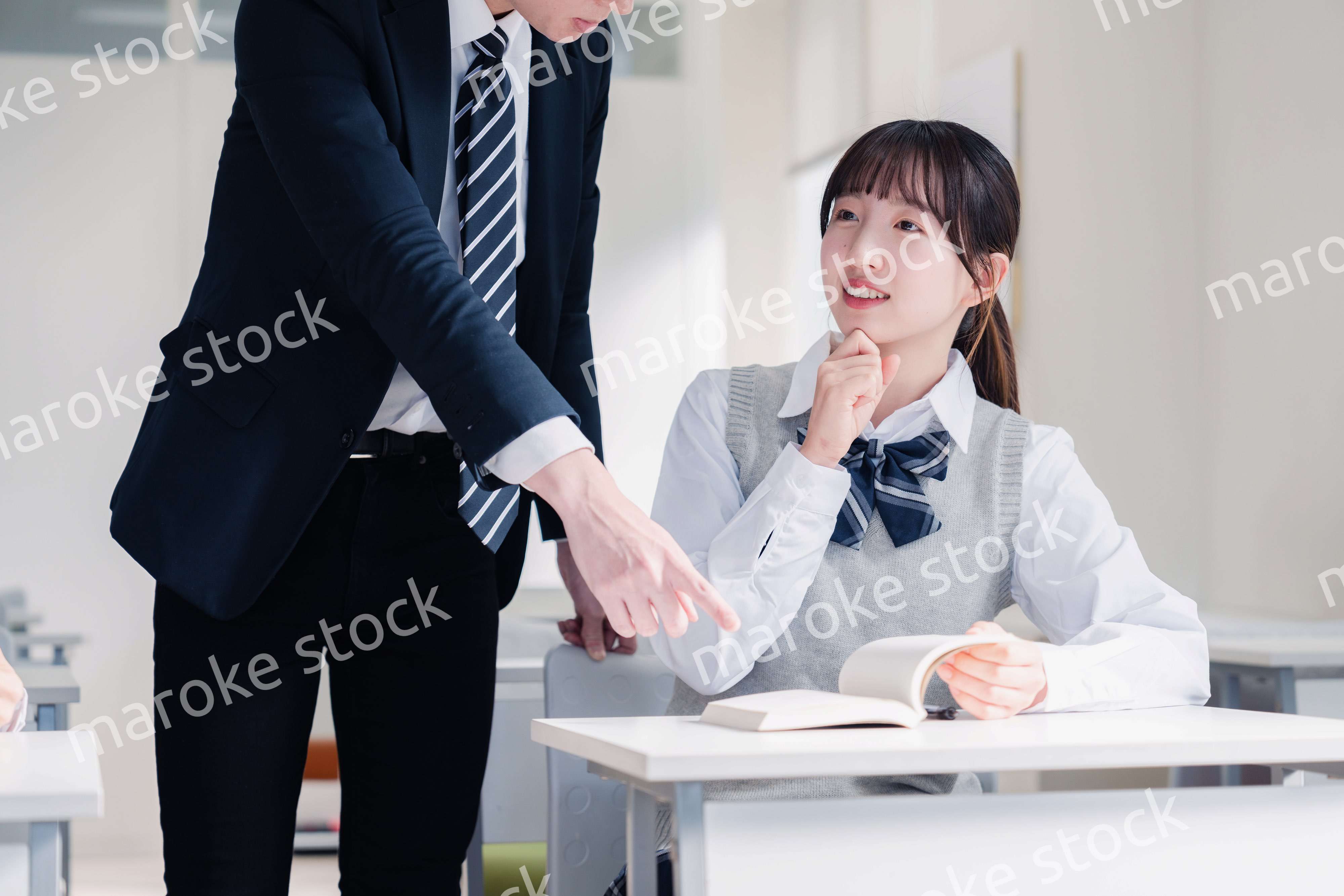 教室で先生に質問をする女子高生