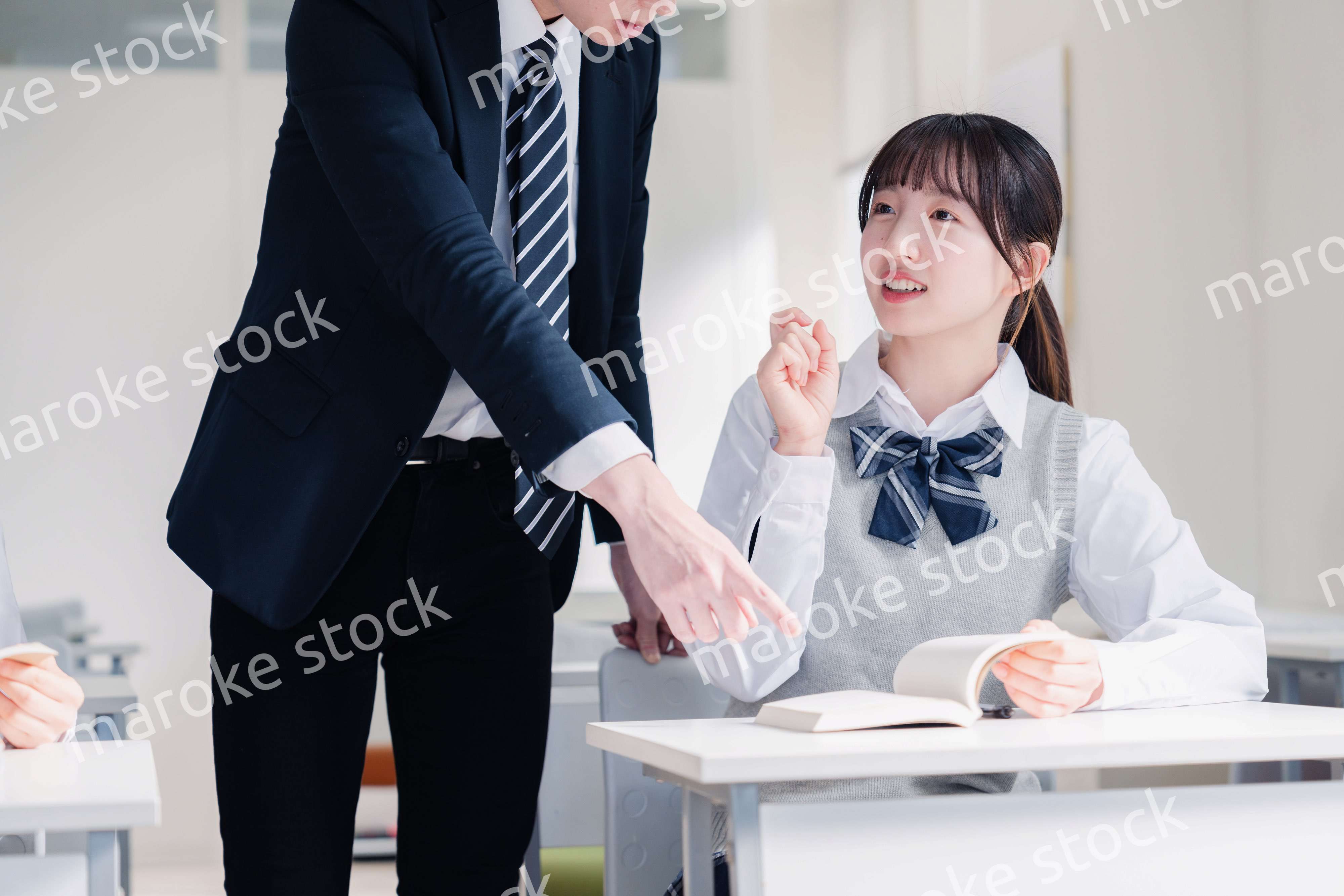 教室で先生に質問をする女子高生