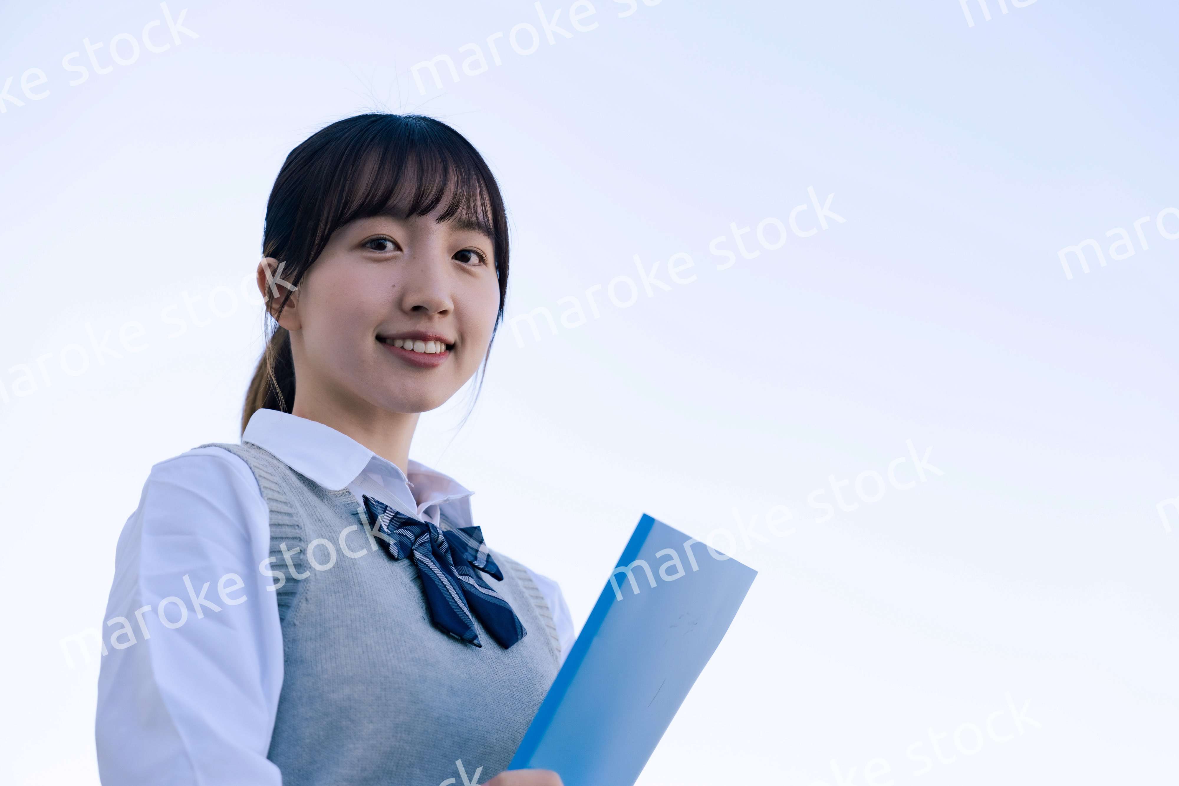 外で遠くを見る制服を着た女子高生