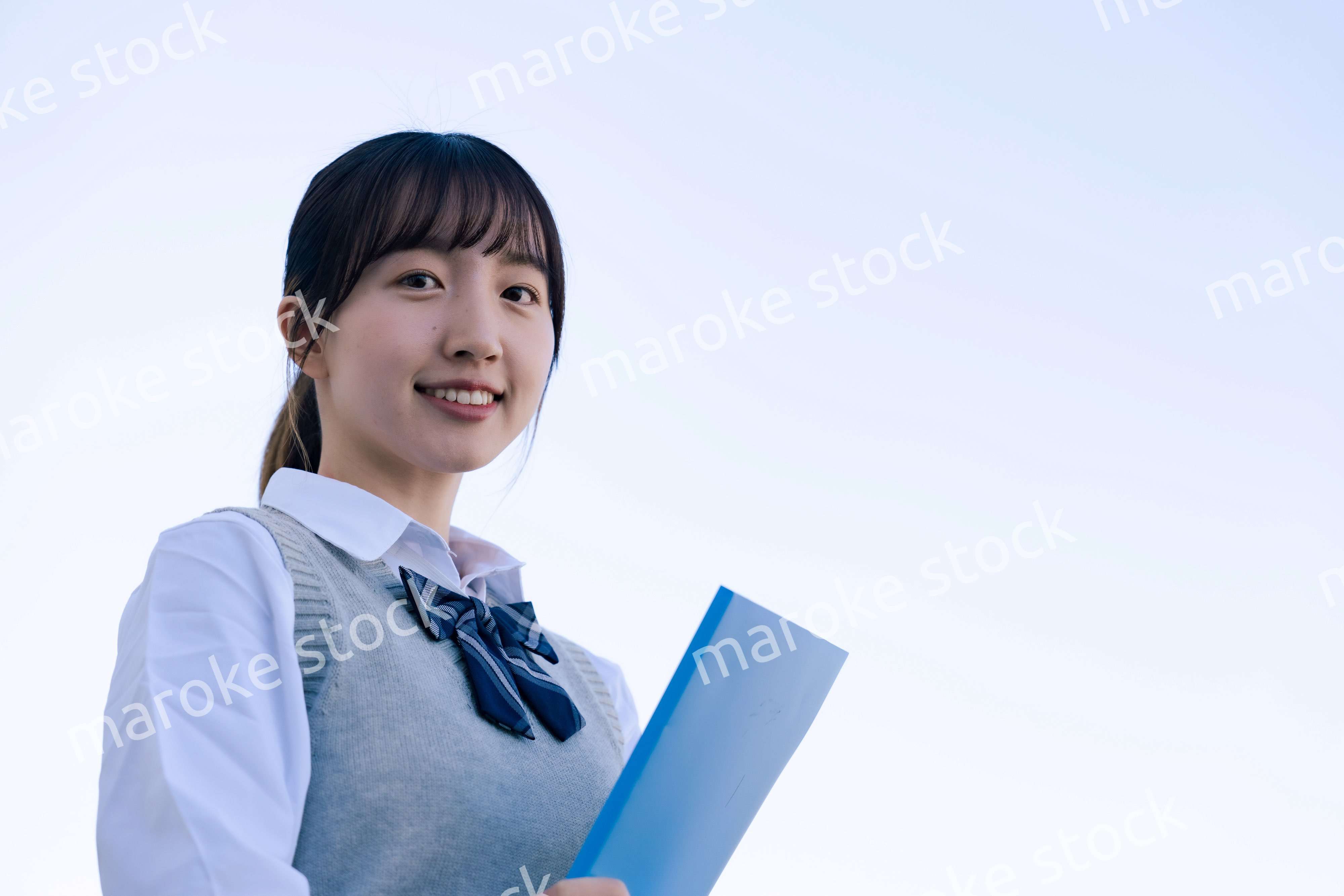 外で遠くを見る制服を着た女子高生