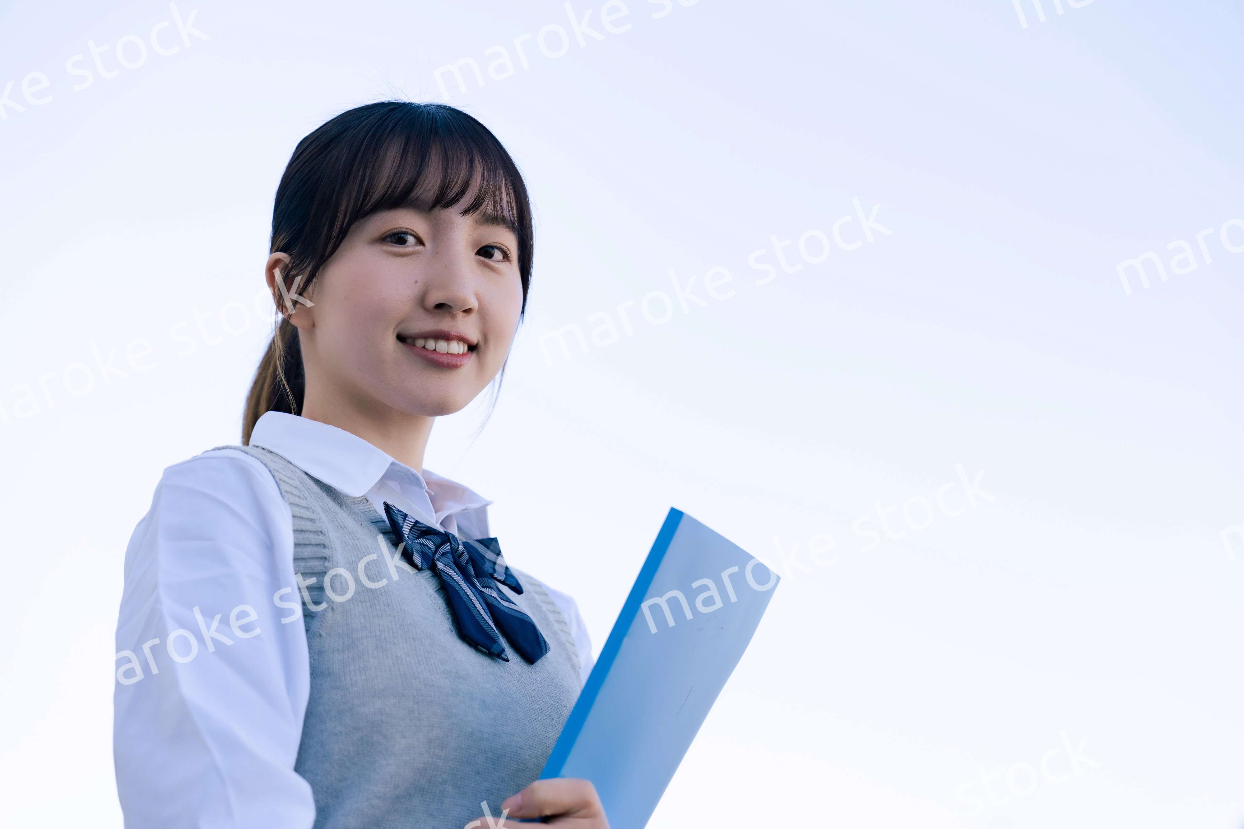 外で遠くを見る制服を着た女子高生