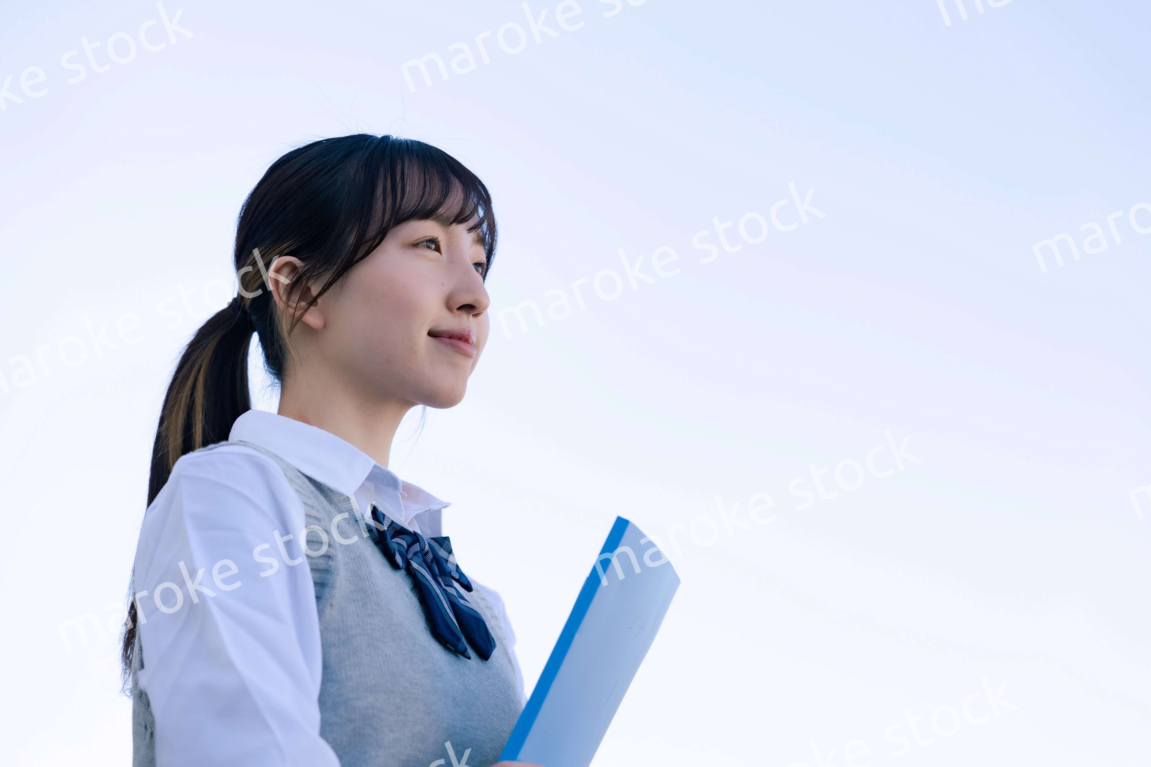 外で遠くを見る制服を着た女子高生