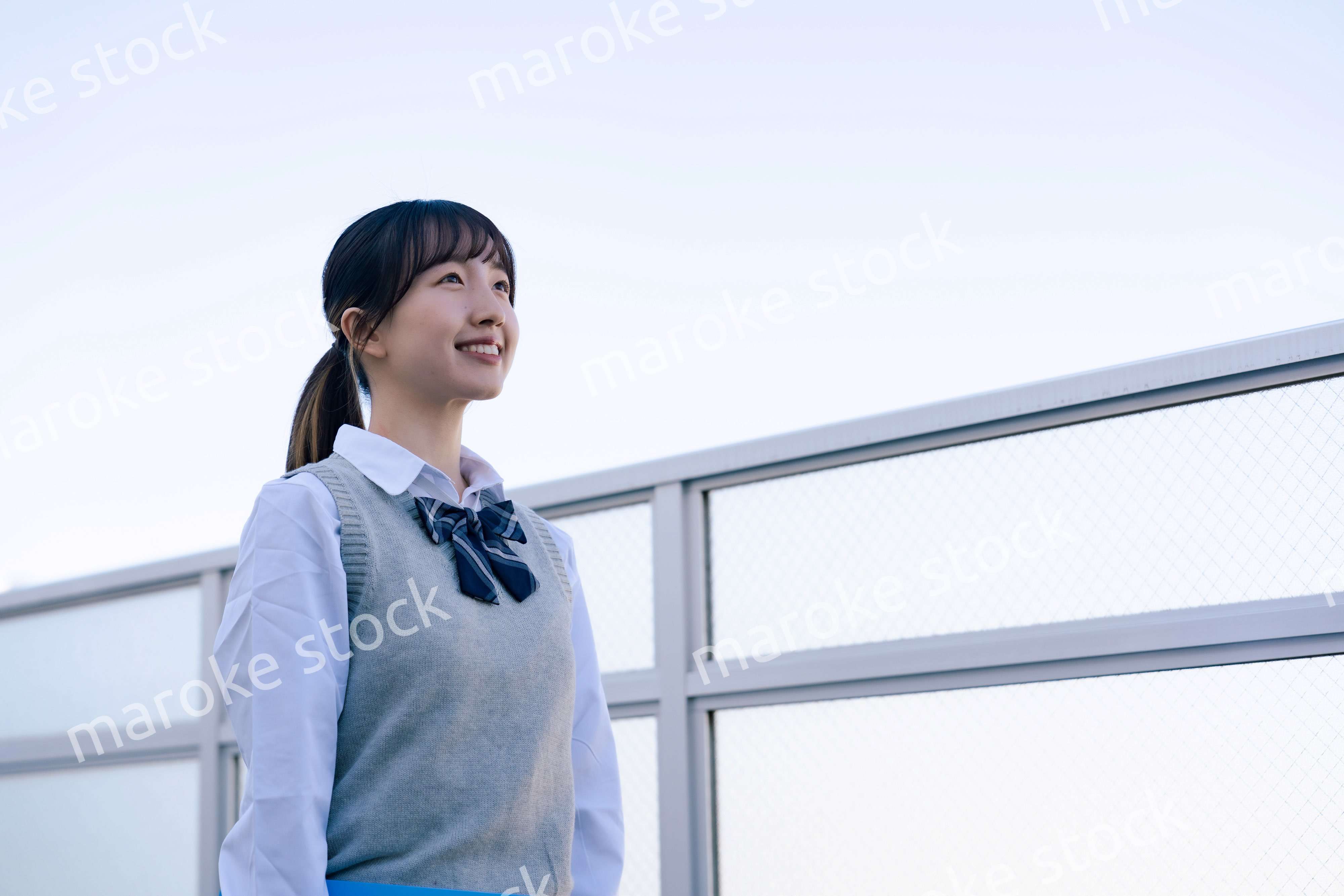 外で遠くを見る制服を着た女子高生