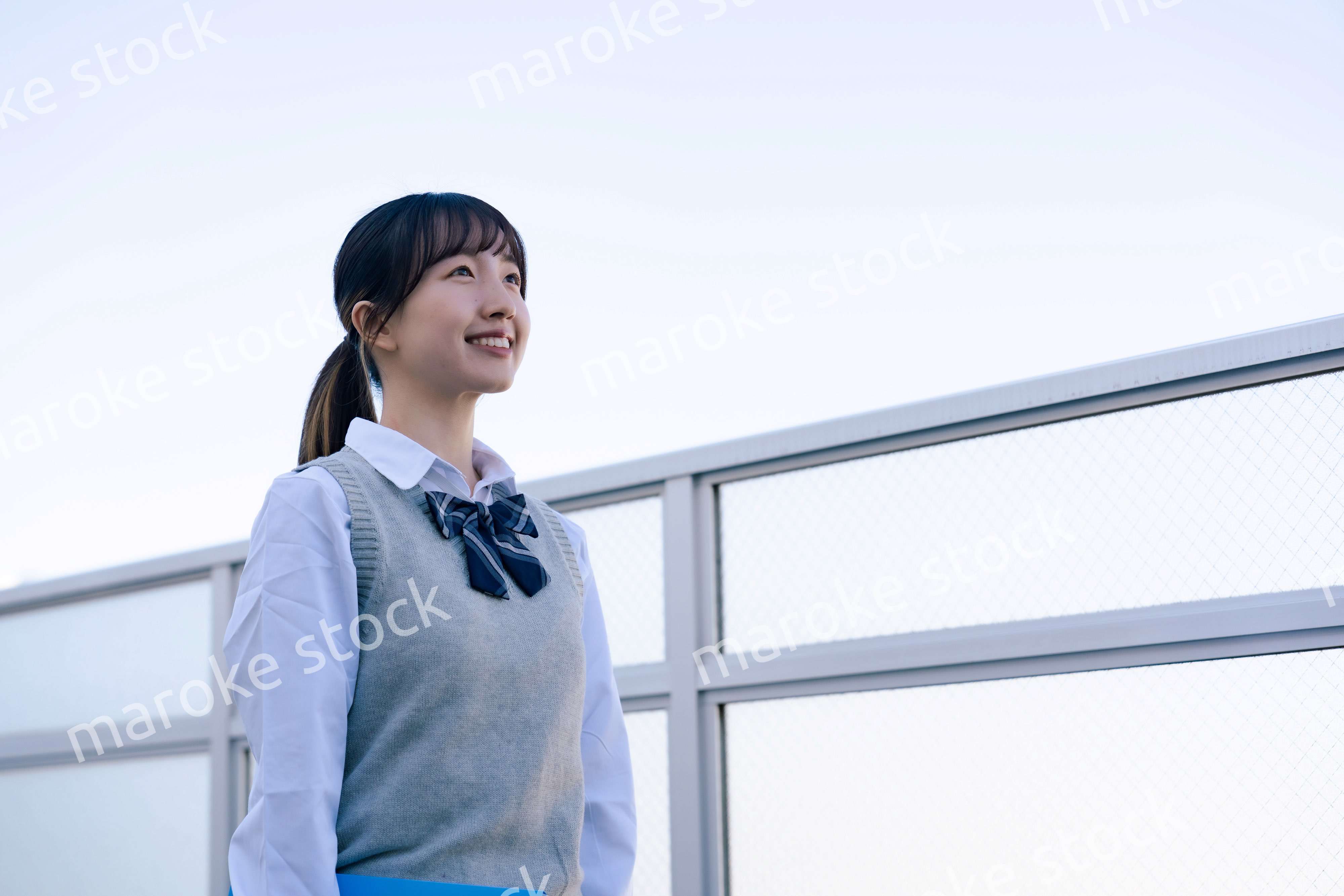 外で遠くを見る制服を着た女子高生