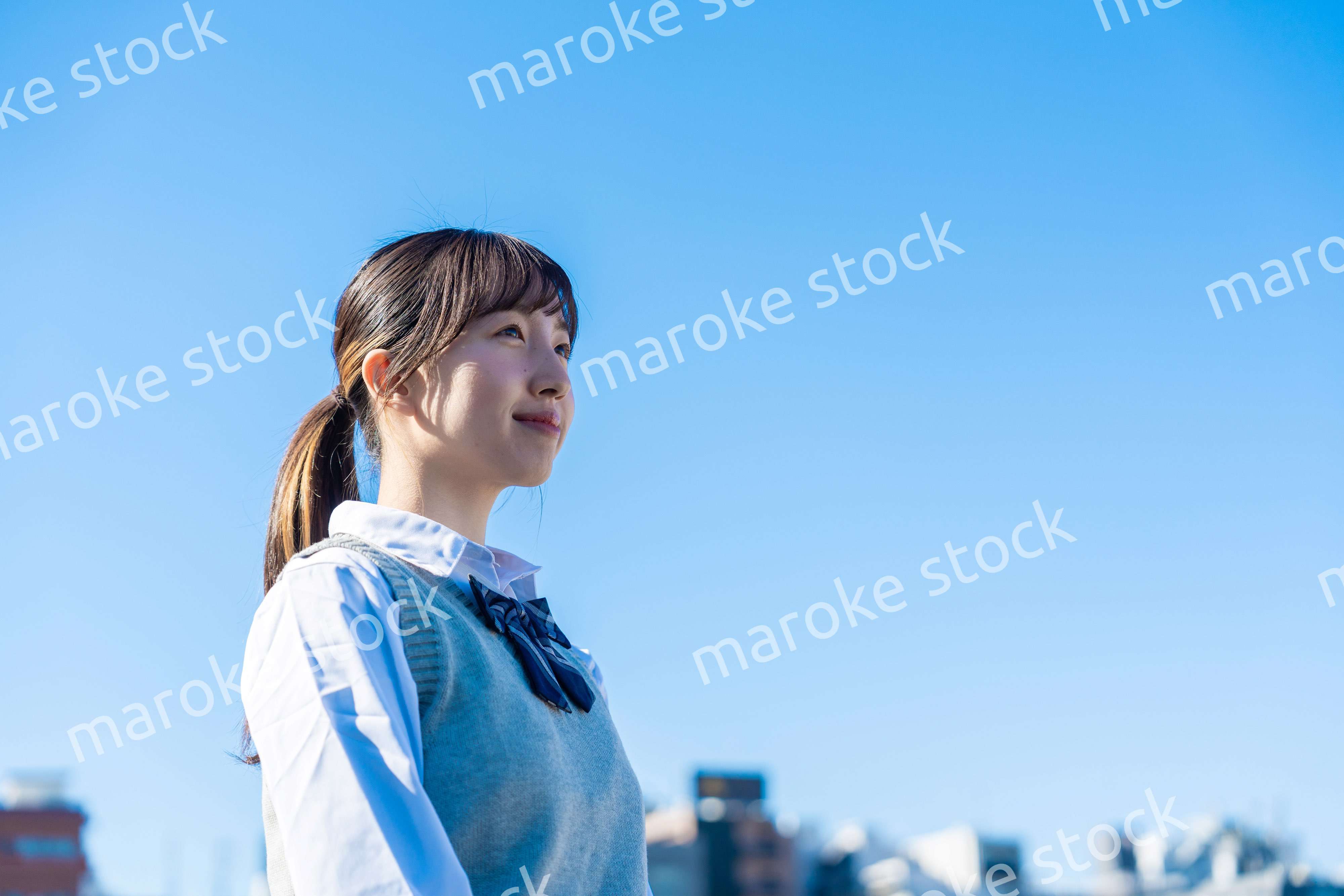 外で遠くを見る制服を着た女子高生