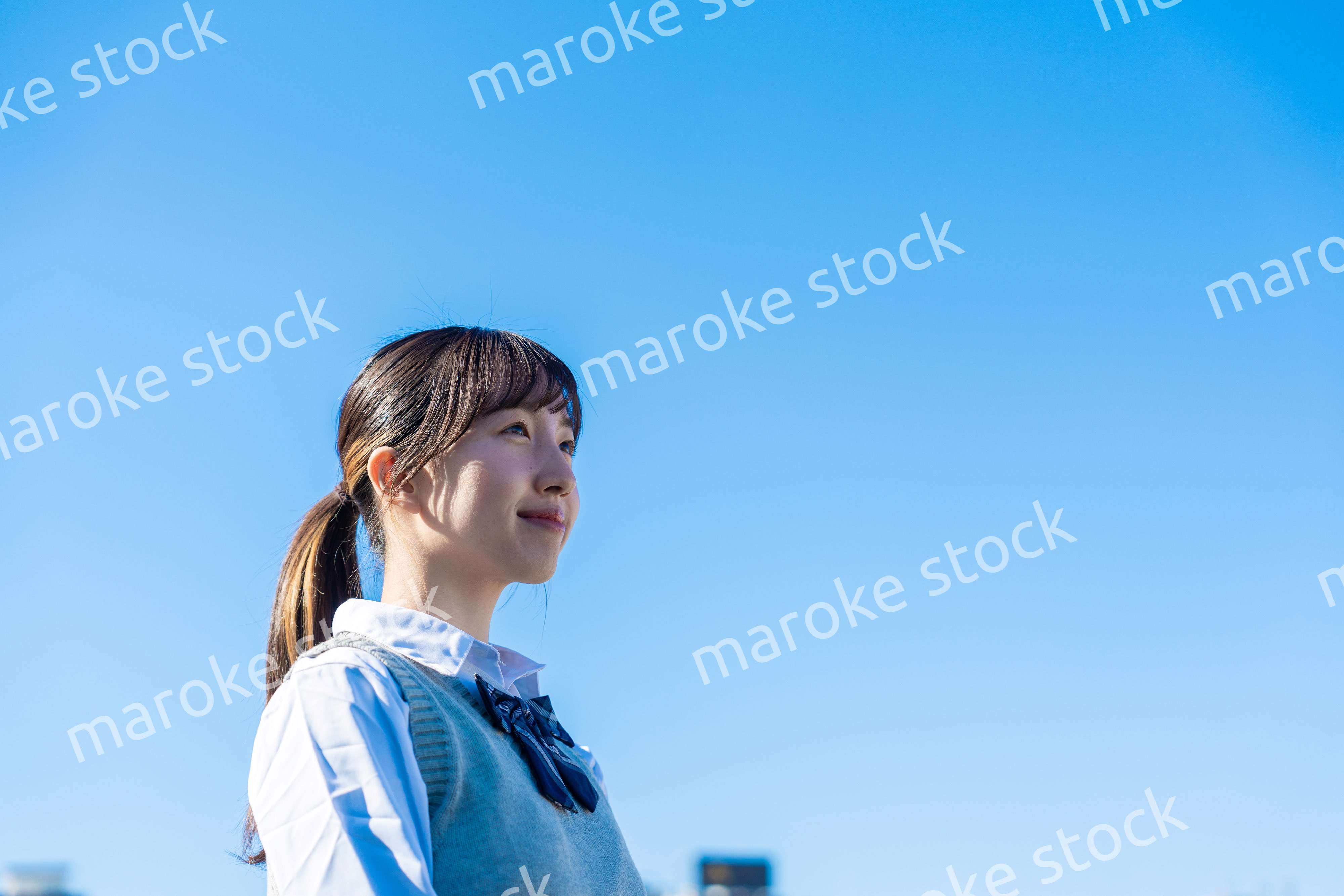 外で遠くを見る制服を着た女子高生