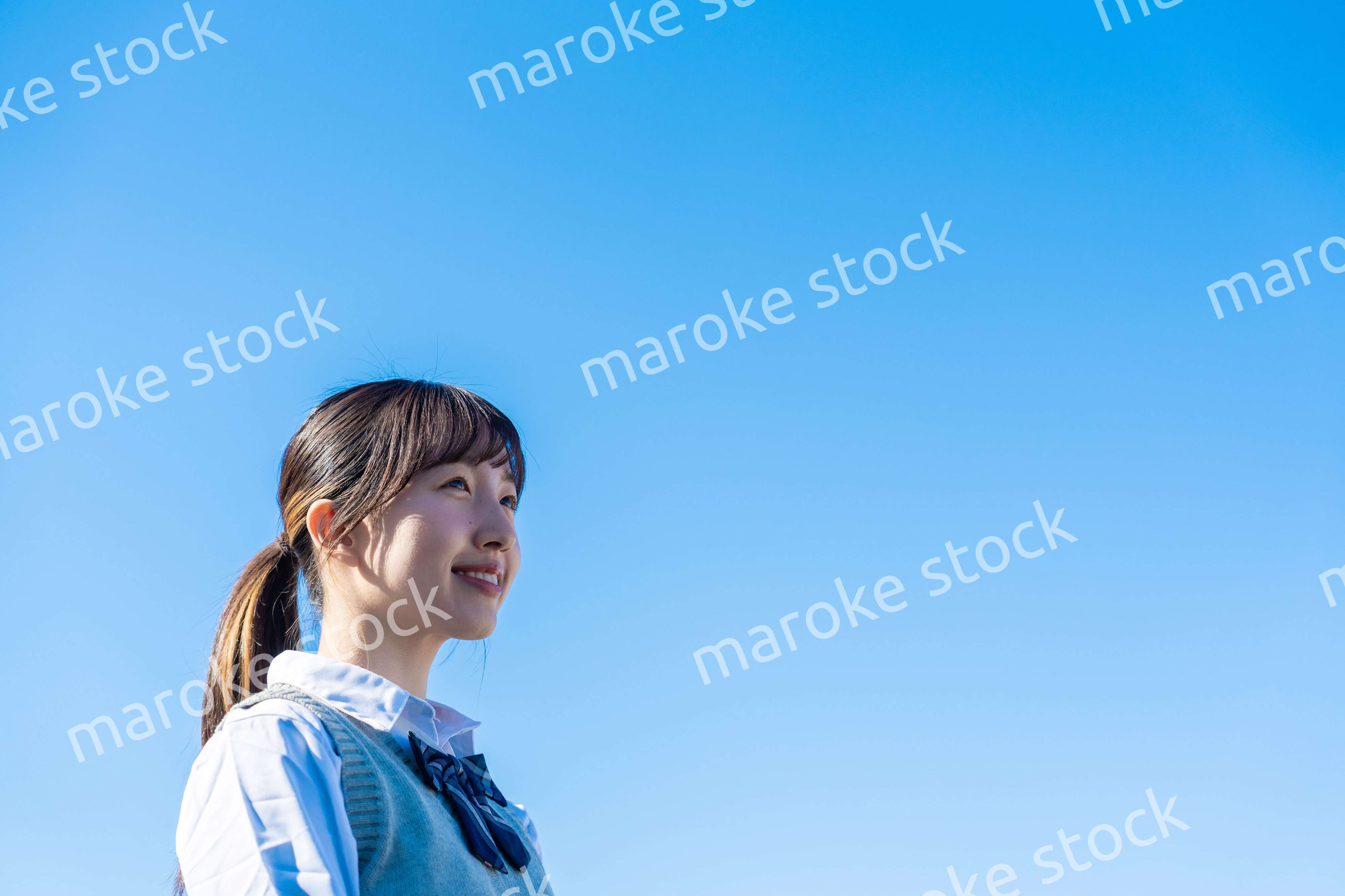 外で遠くを見る制服を着た女子高生