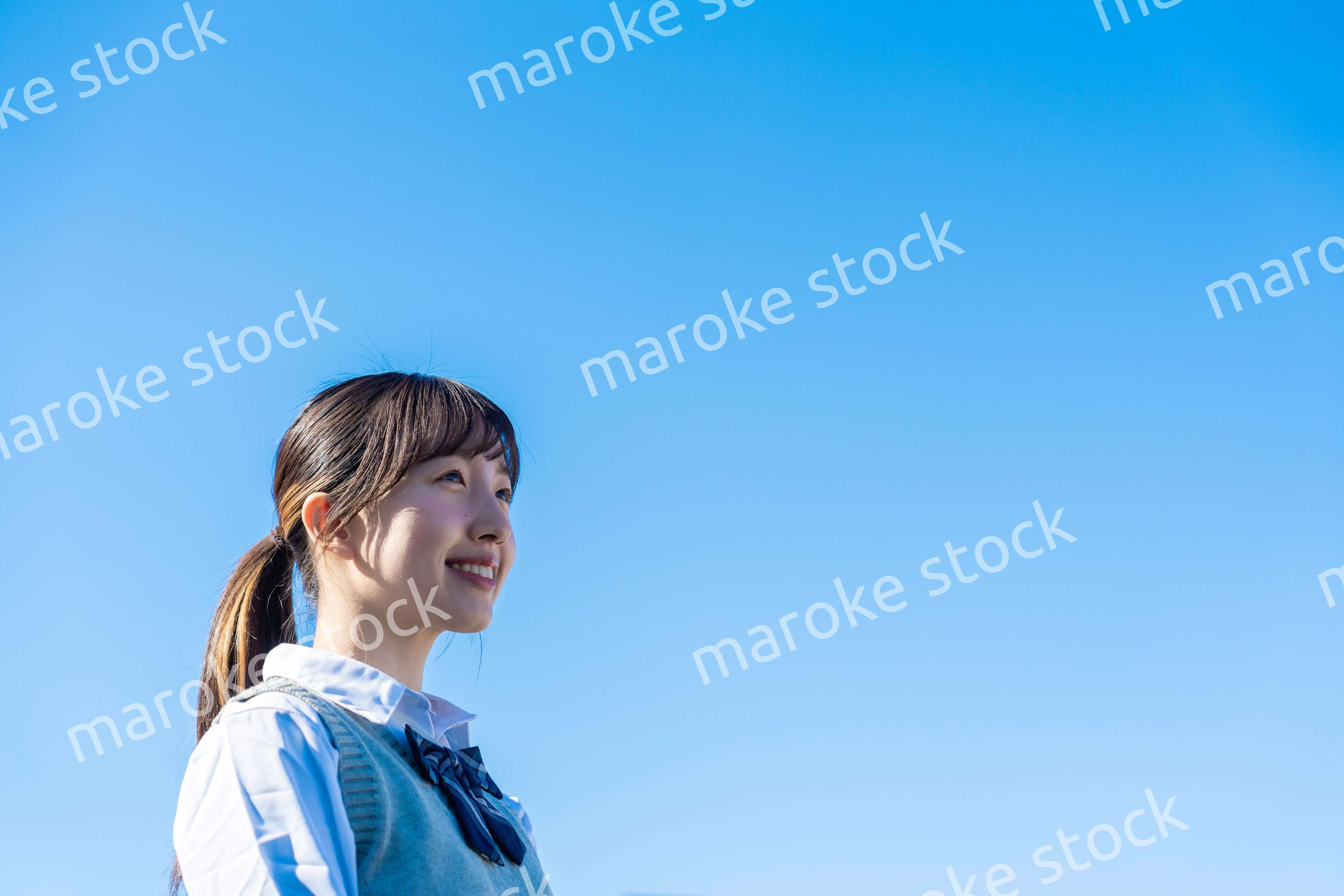 外で遠くを見る制服を着た女子高生