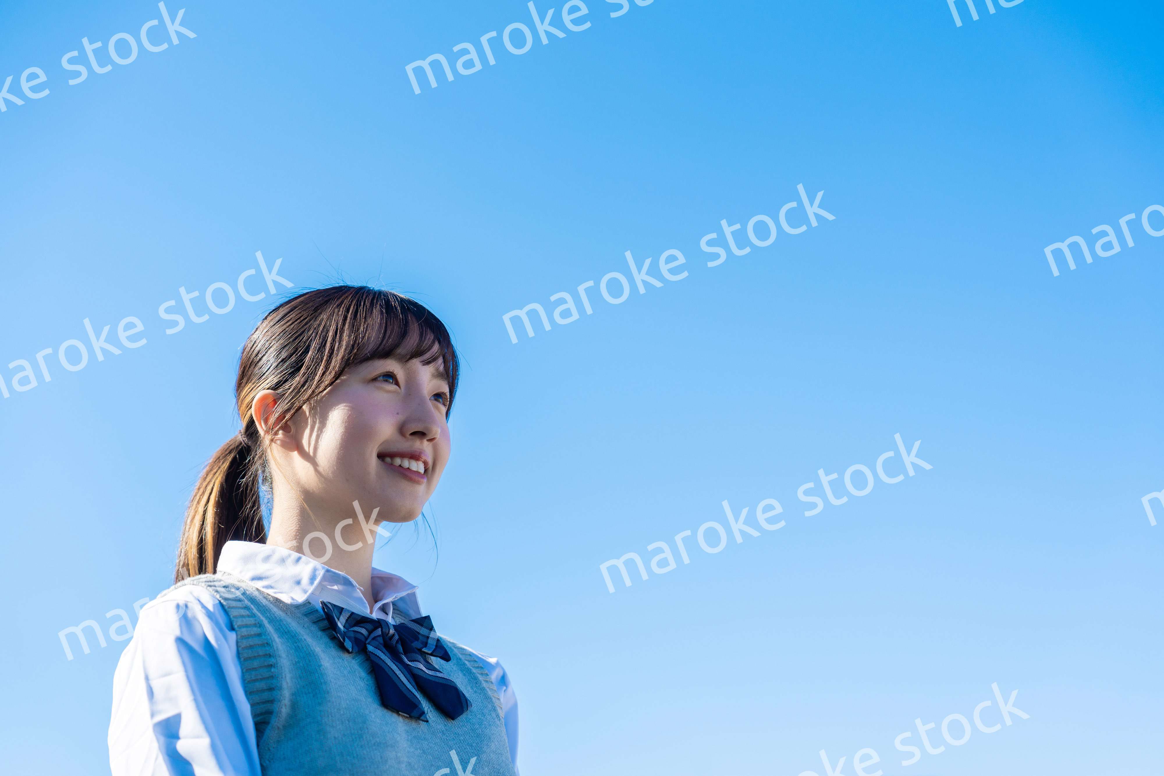 外で遠くを見る制服を着た女子高生