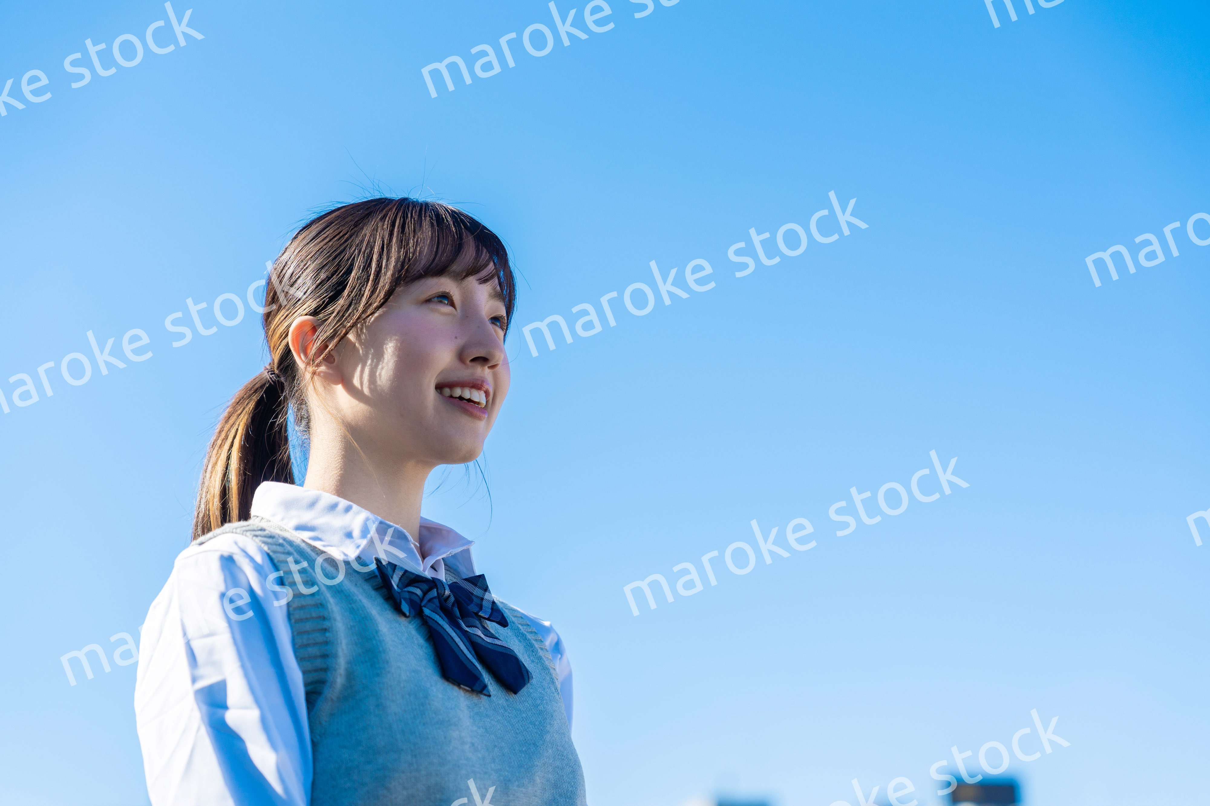 外で遠くを見る制服を着た女子高生
