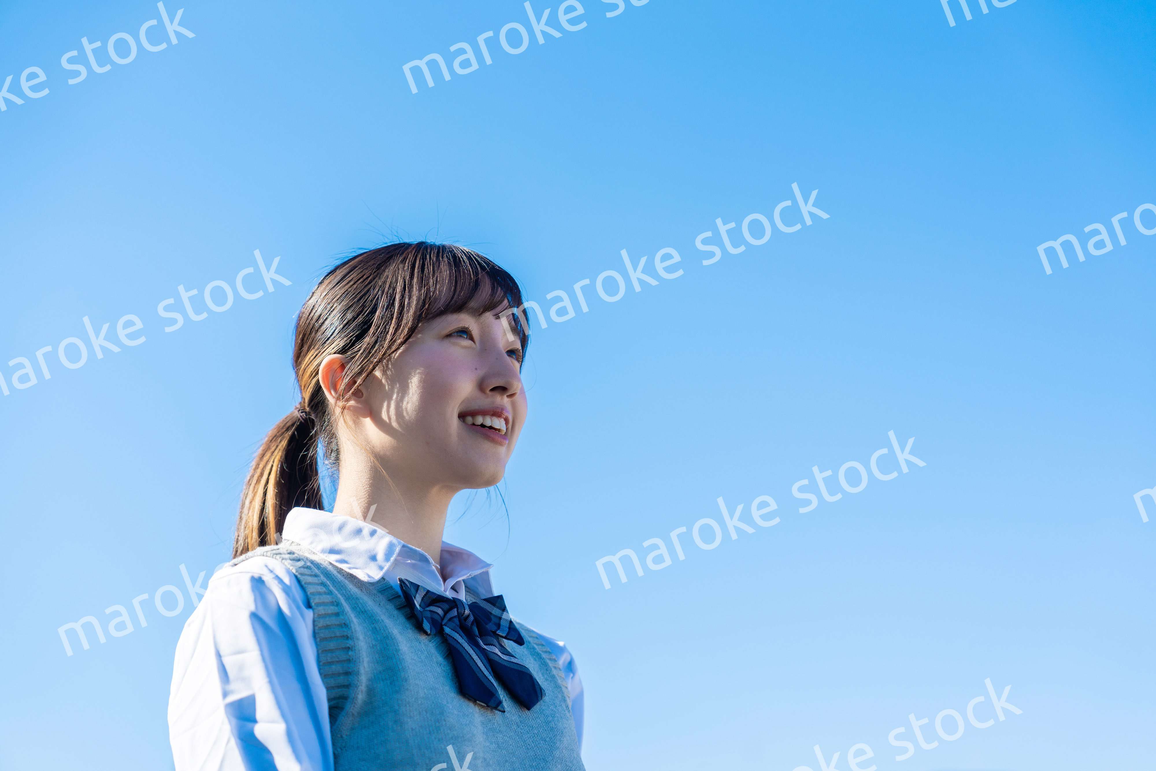 外で遠くを見る制服を着た女子高生