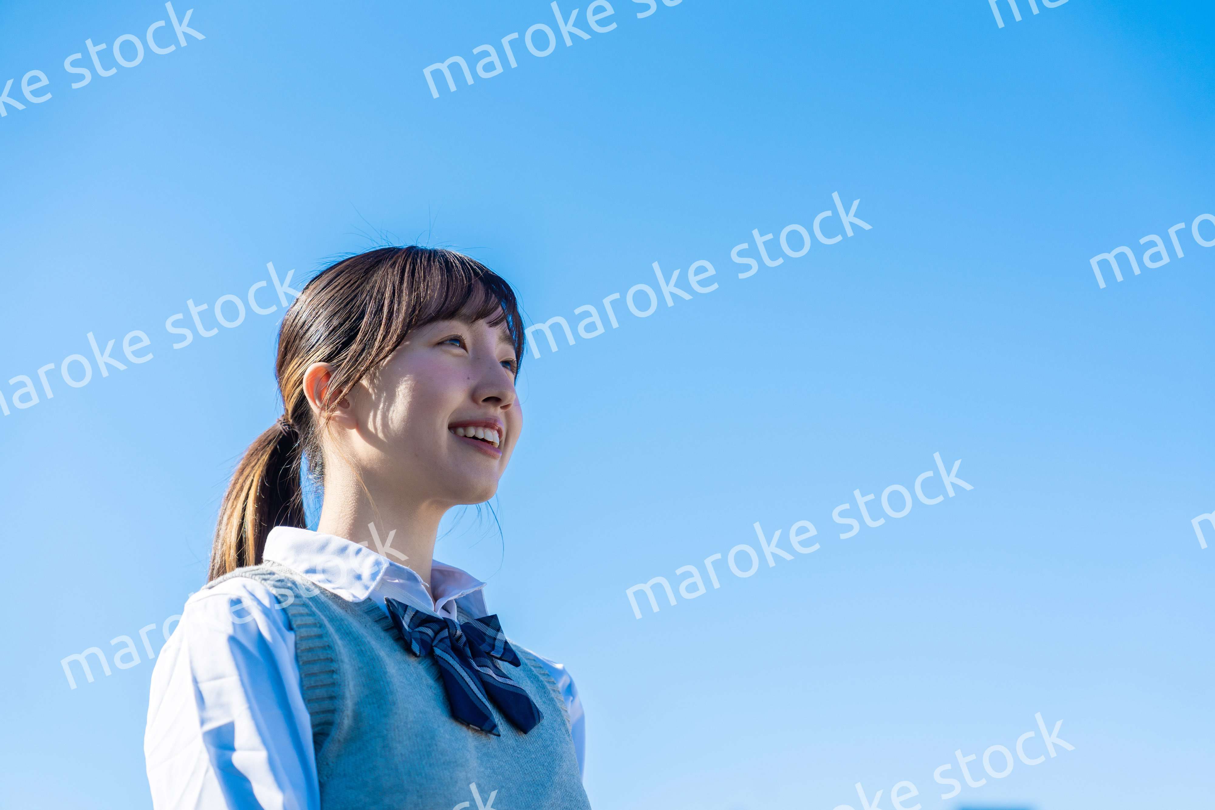 外で遠くを見る制服を着た女子高生