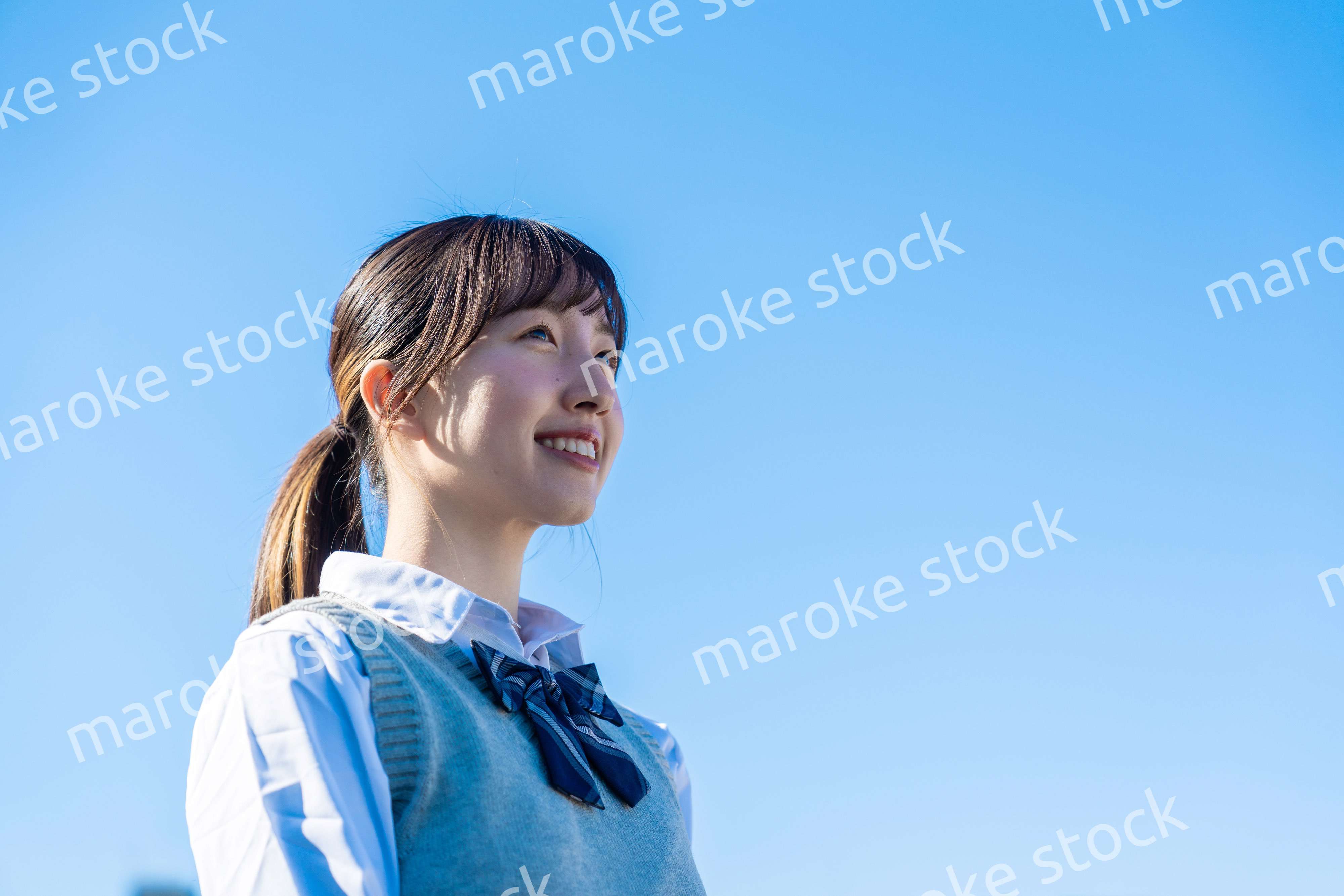 外で遠くを見る制服を着た女子高生