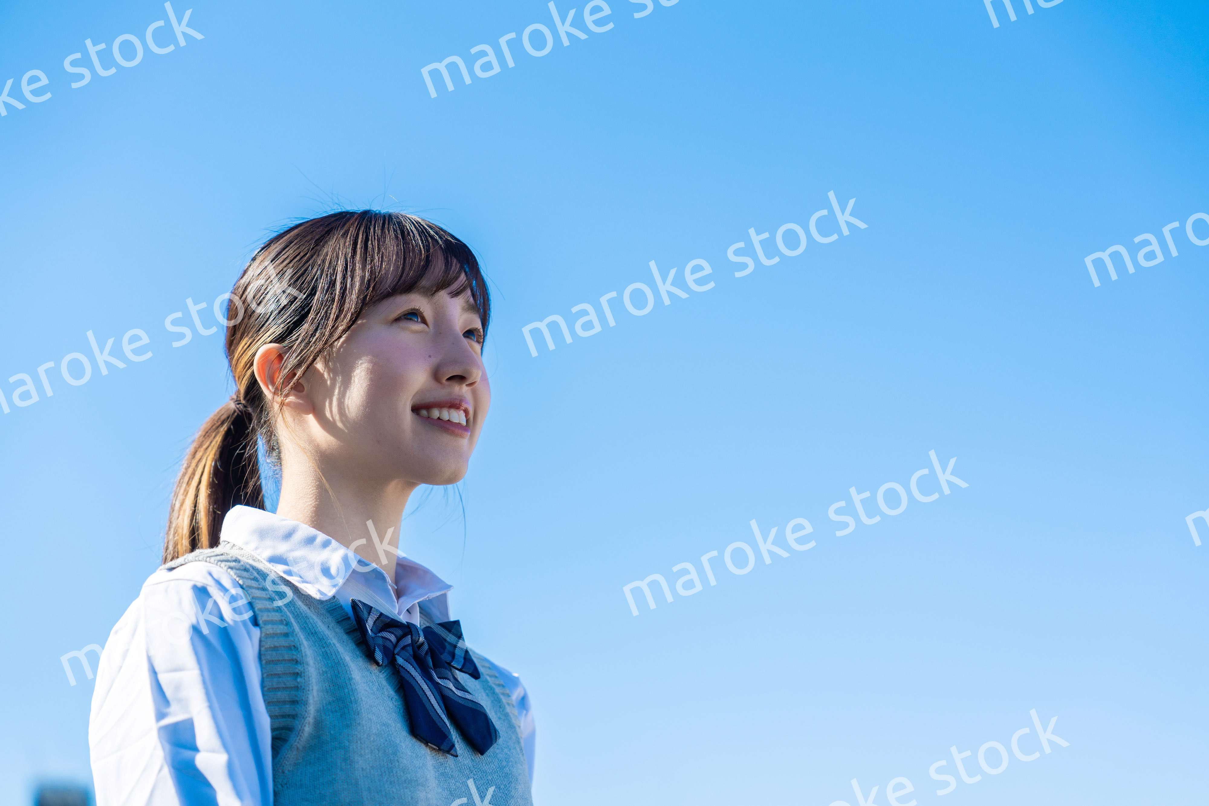 外で遠くを見る制服を着た女子高生