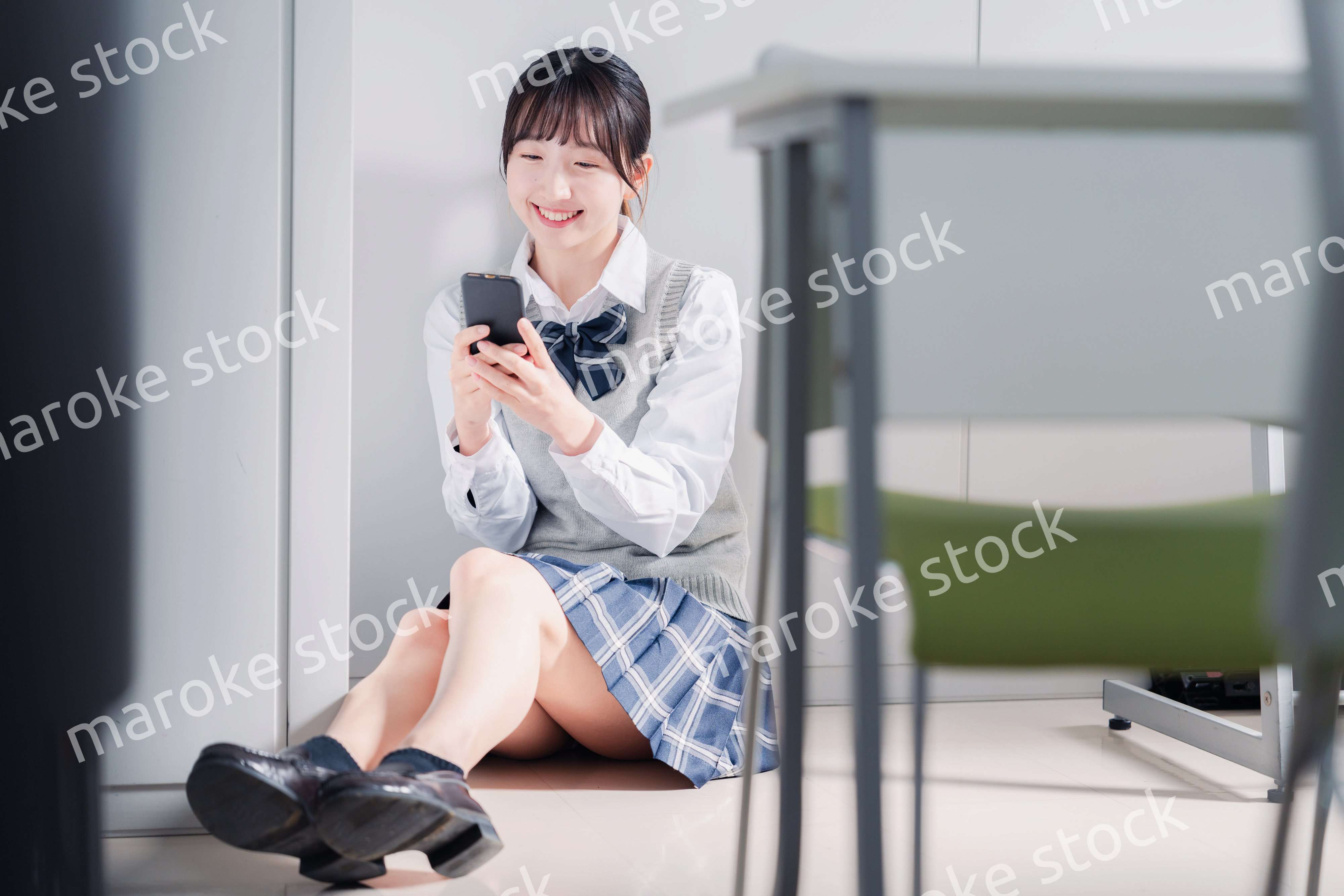 教室で笑顔でスマホを使う女子高生