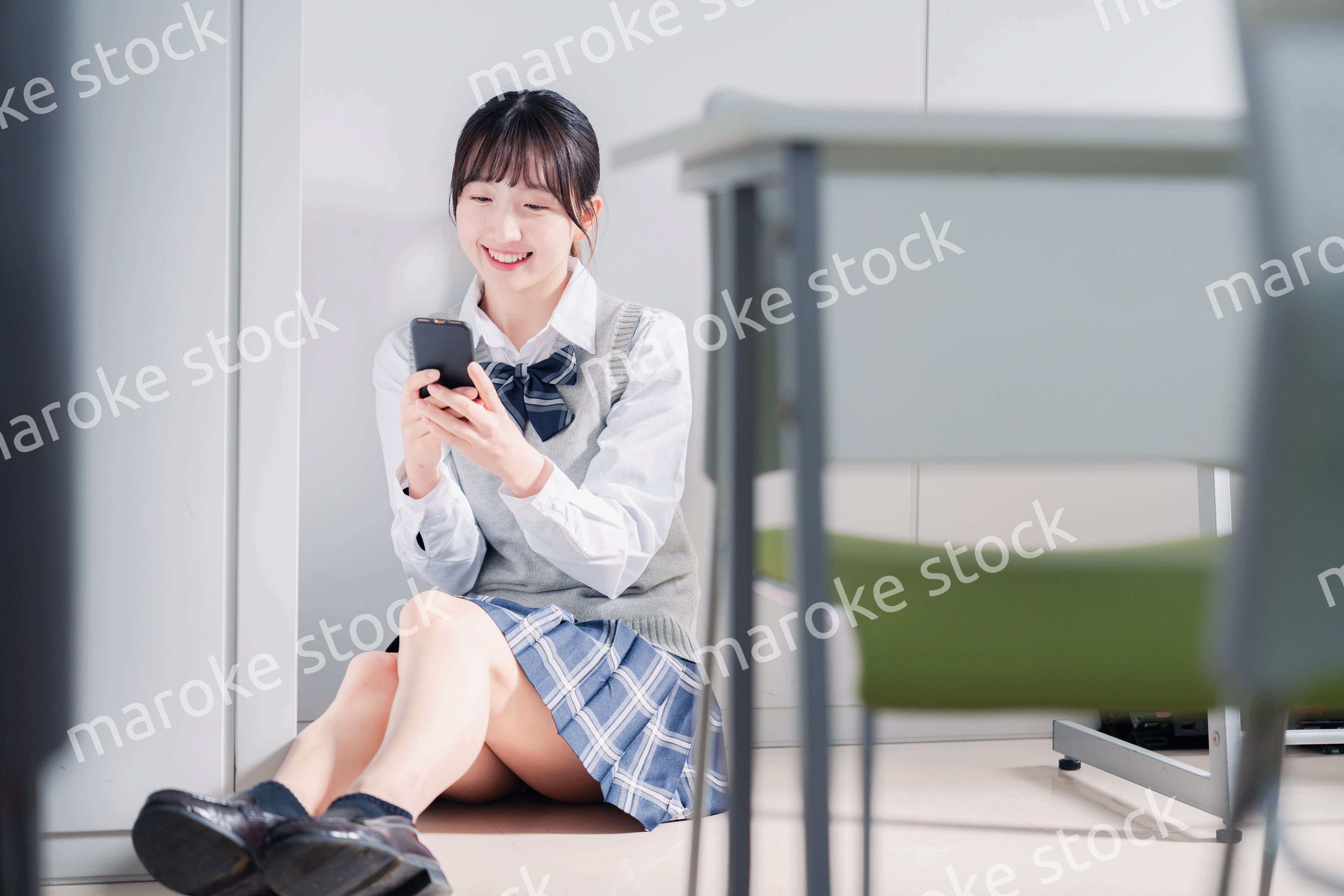 教室で笑顔でスマホを使う女子高生