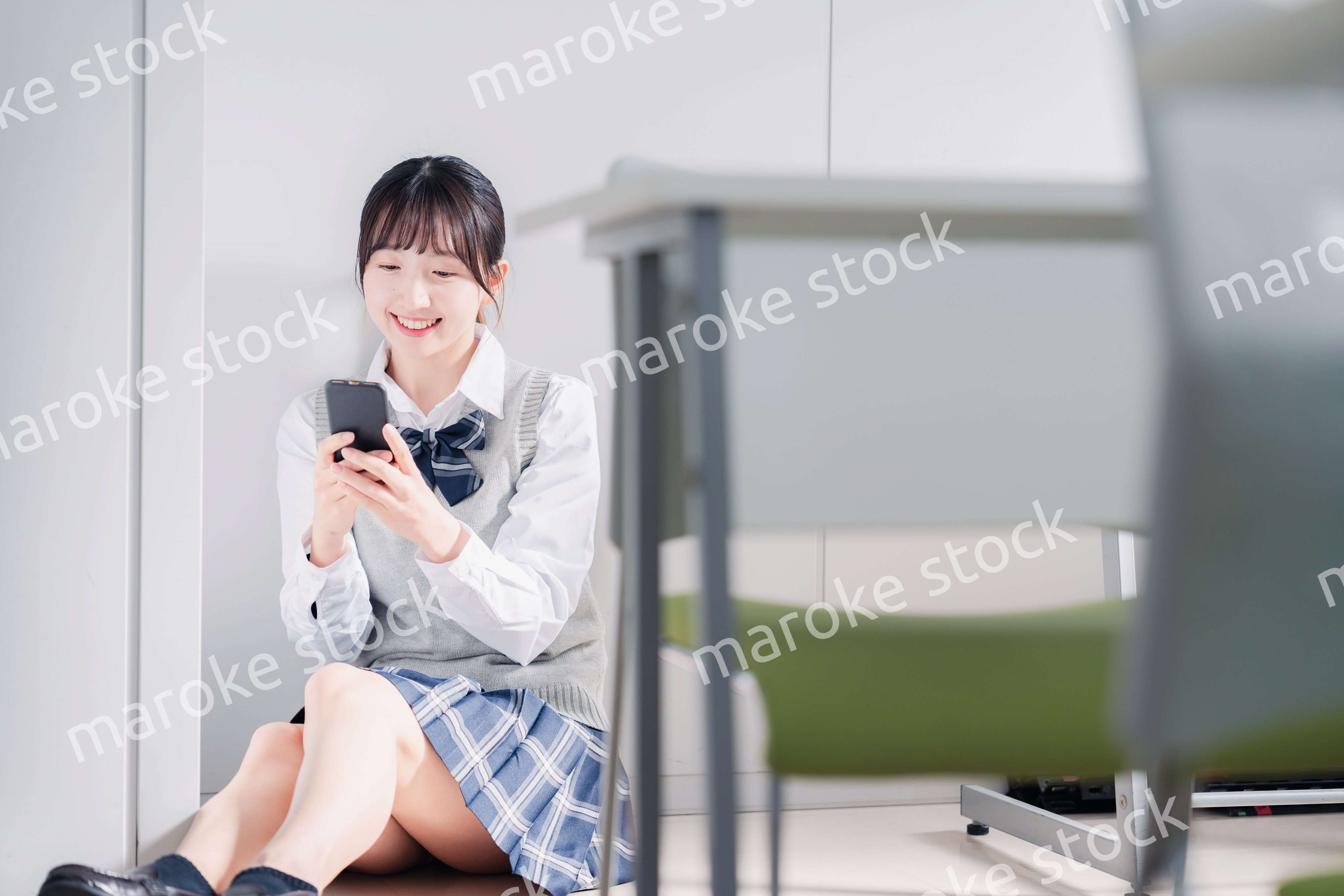 教室で笑顔でスマホを使う女子高生