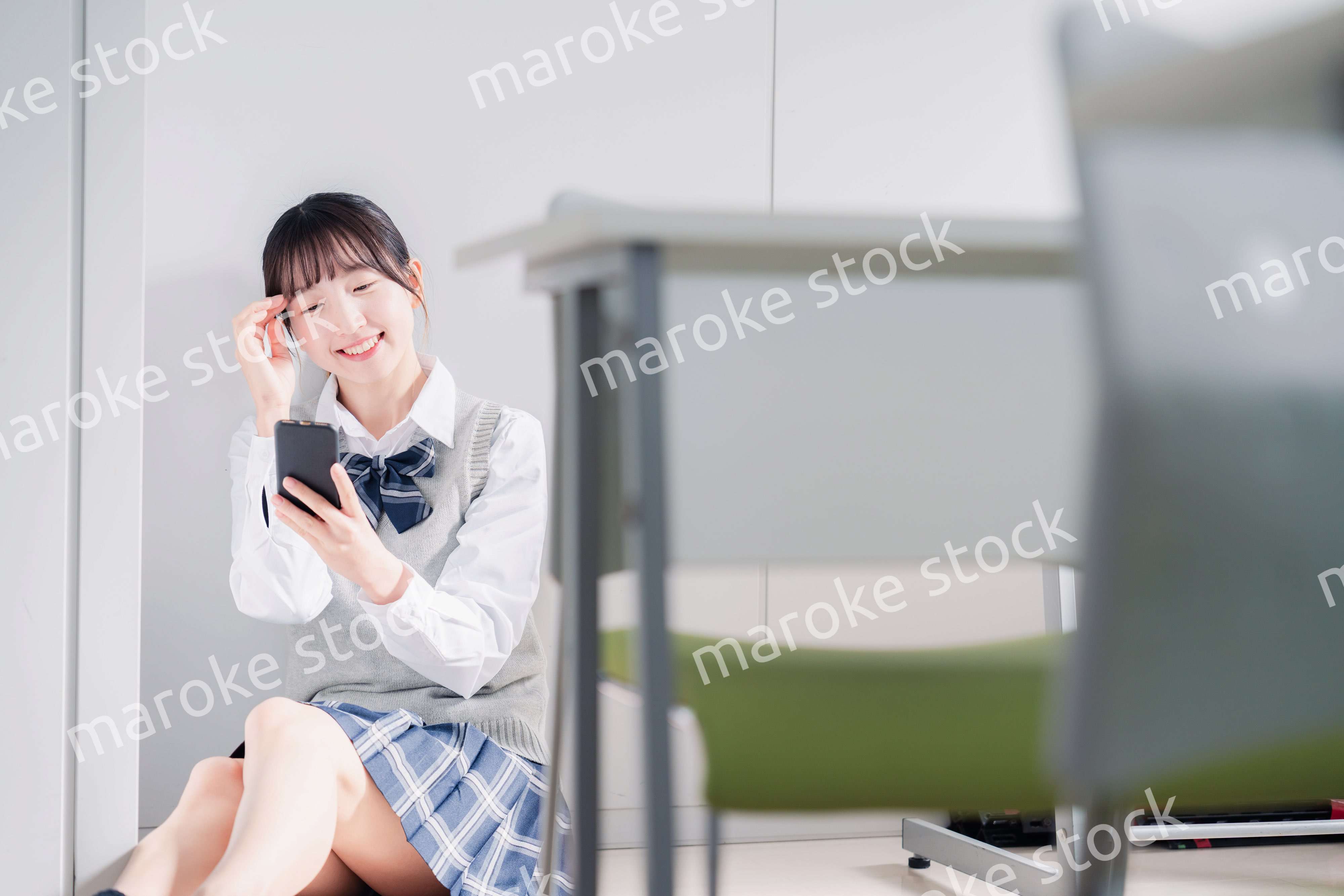 教室で笑顔でスマホを使う女子高生