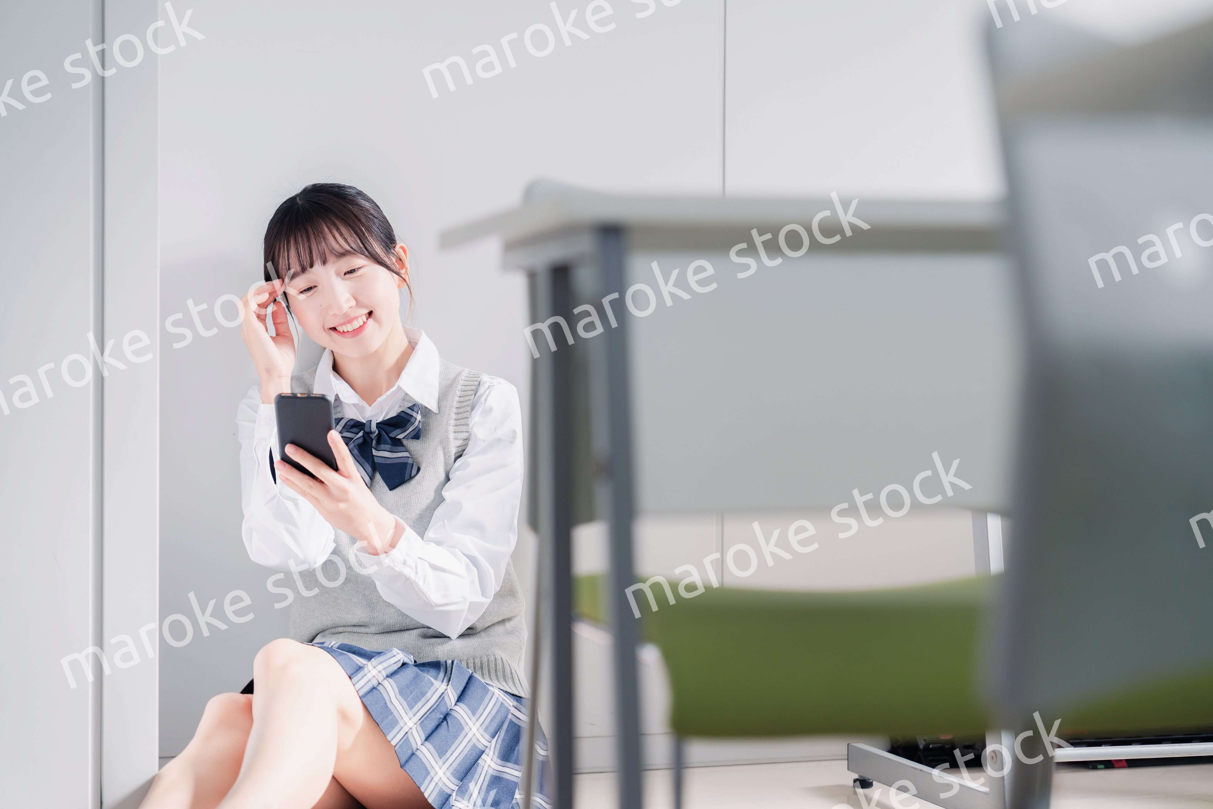 教室で笑顔でスマホを使う女子高生