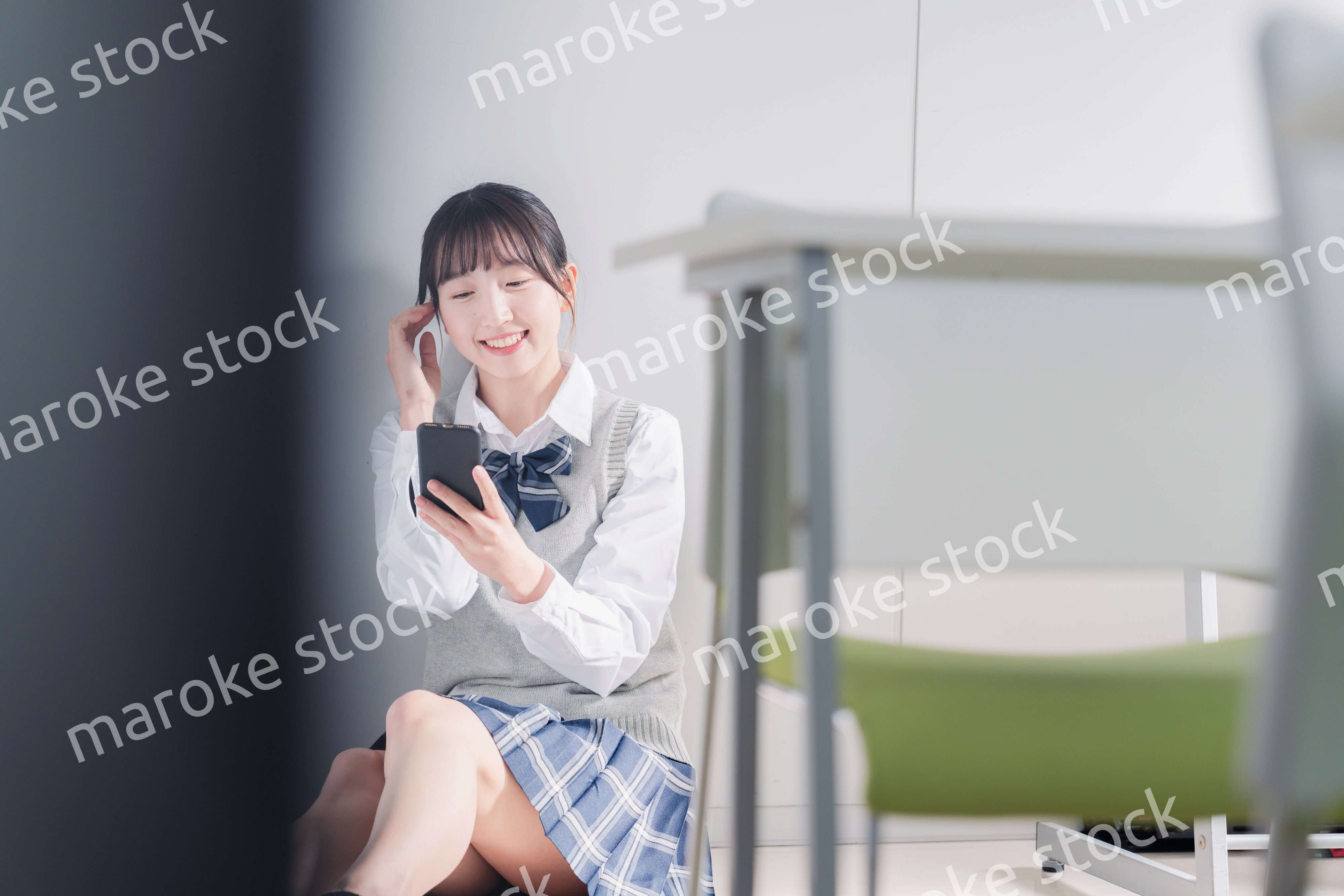 教室で笑顔でスマホを使う女子高生