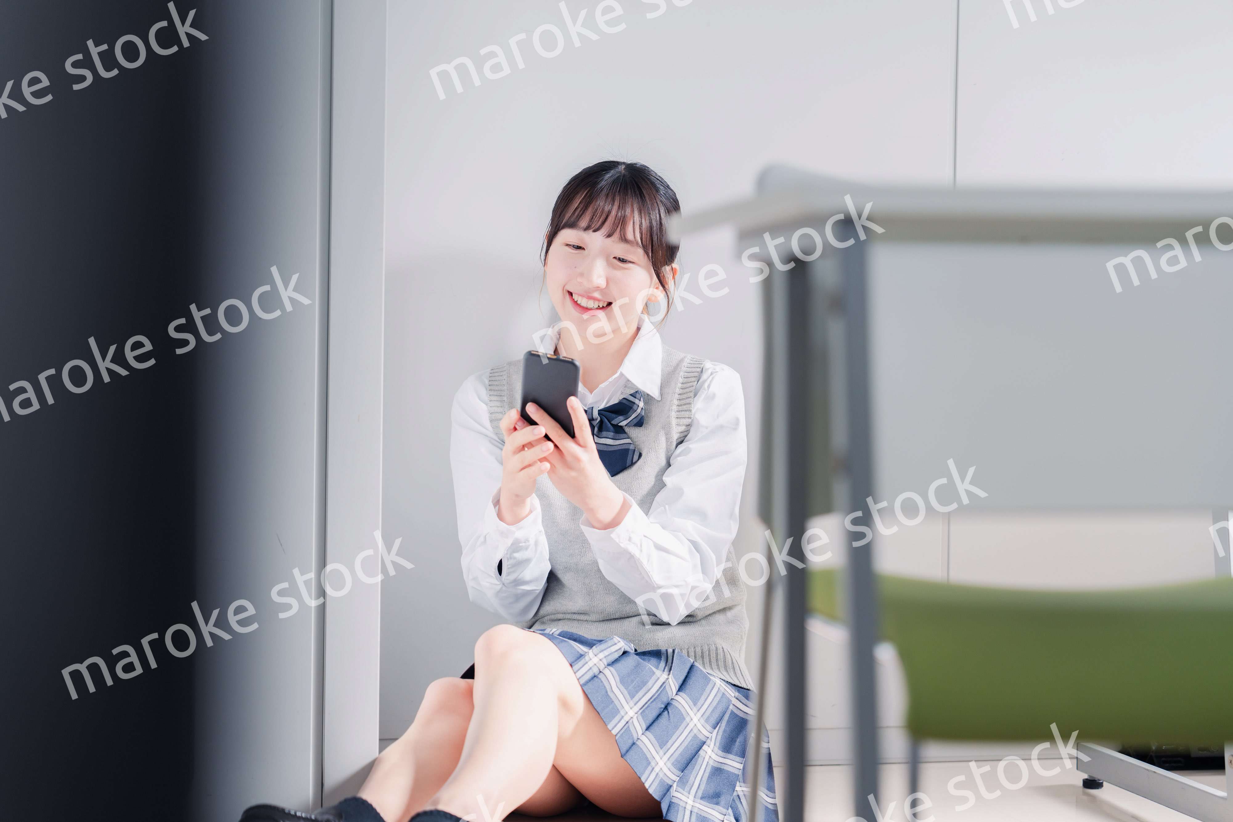 教室で笑顔でスマホを使う女子高生