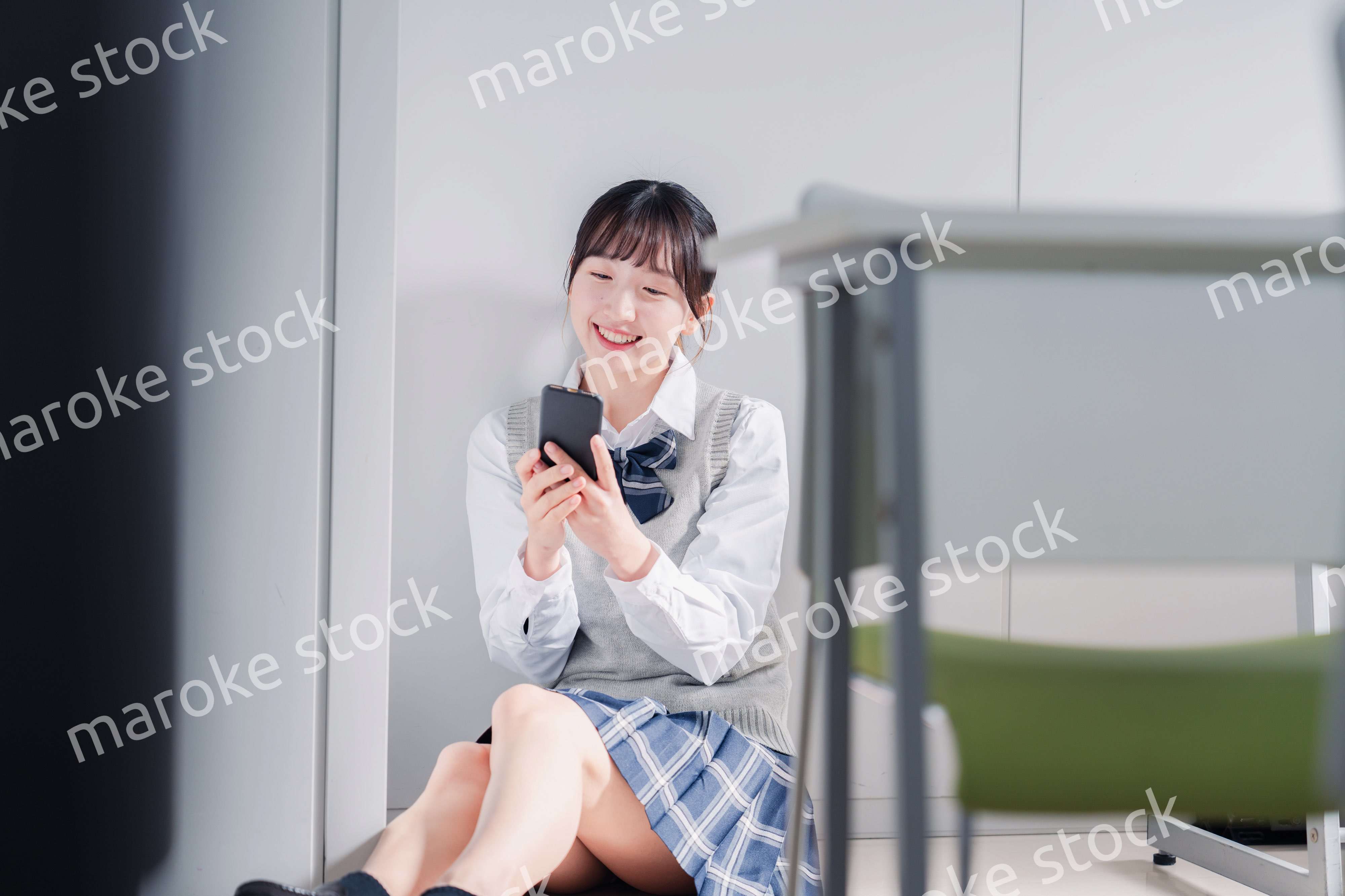 教室で笑顔でスマホを使う女子高生