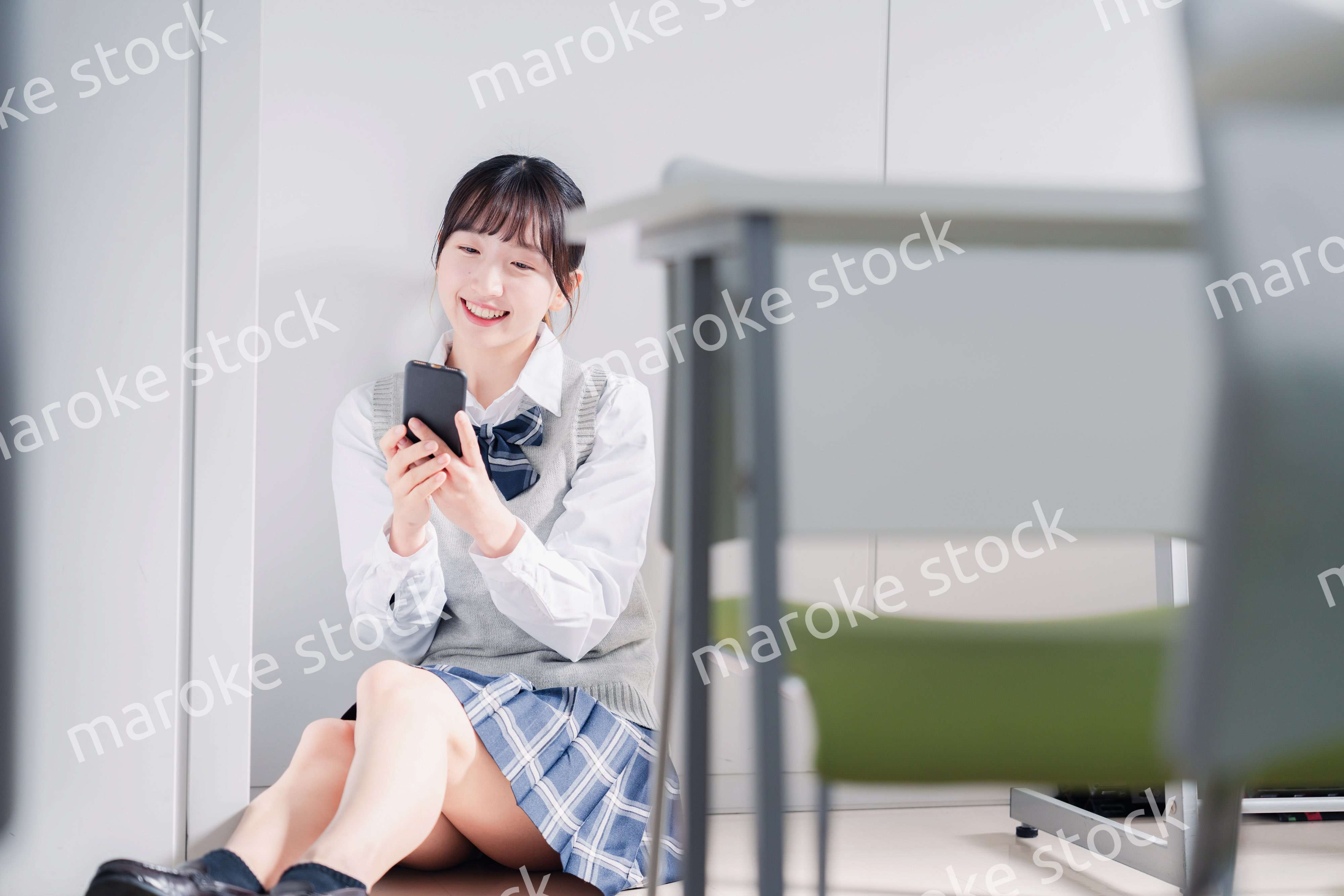 教室で笑顔でスマホを使う女子高生