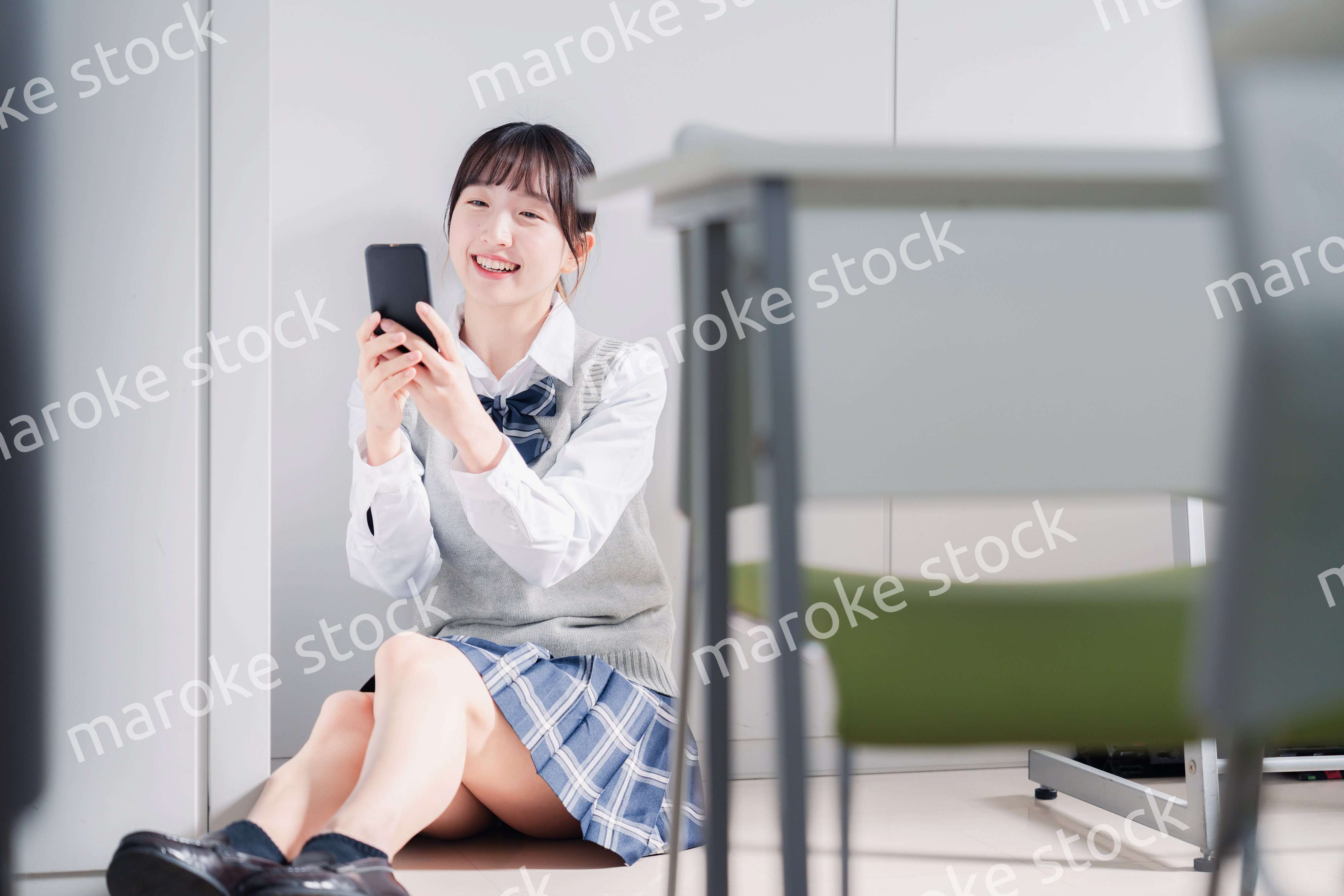 教室で笑顔でスマホを使う女子高生