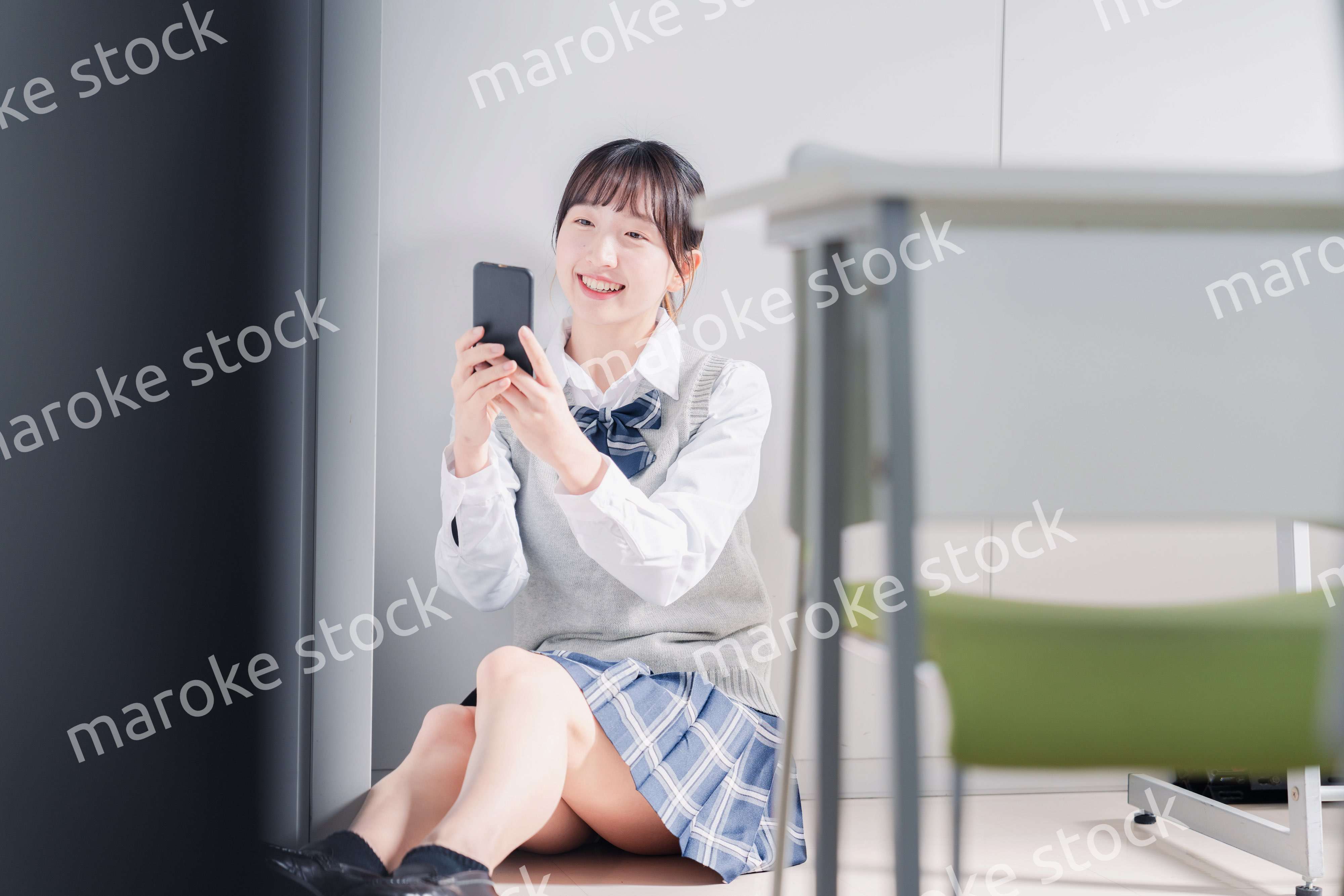 教室で笑顔でスマホを使う女子高生