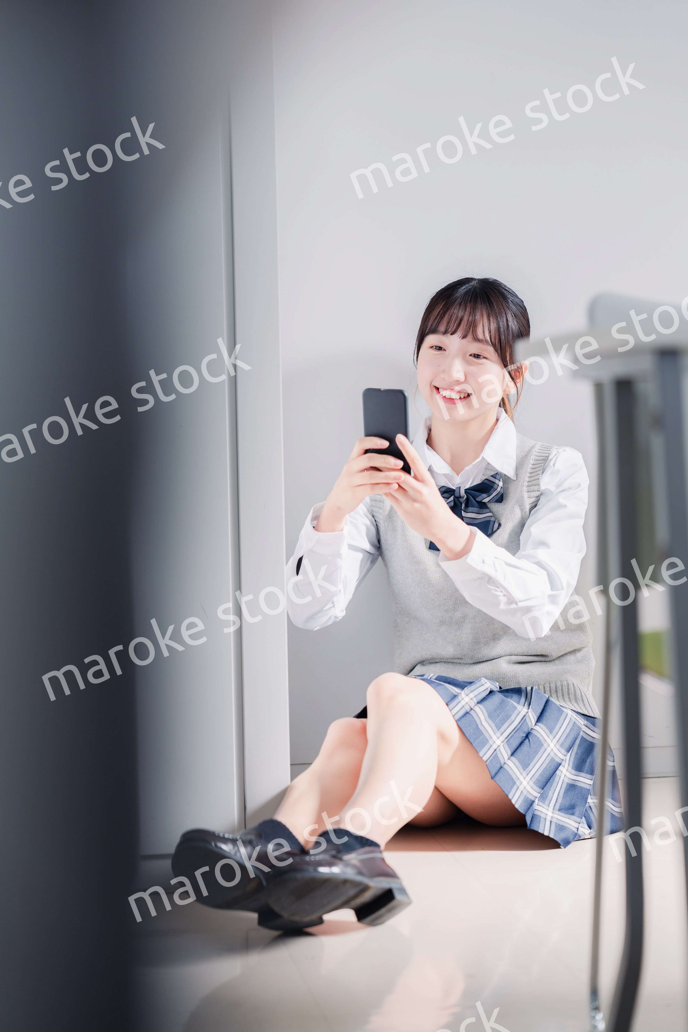 教室で笑顔でスマホを使う女子高生