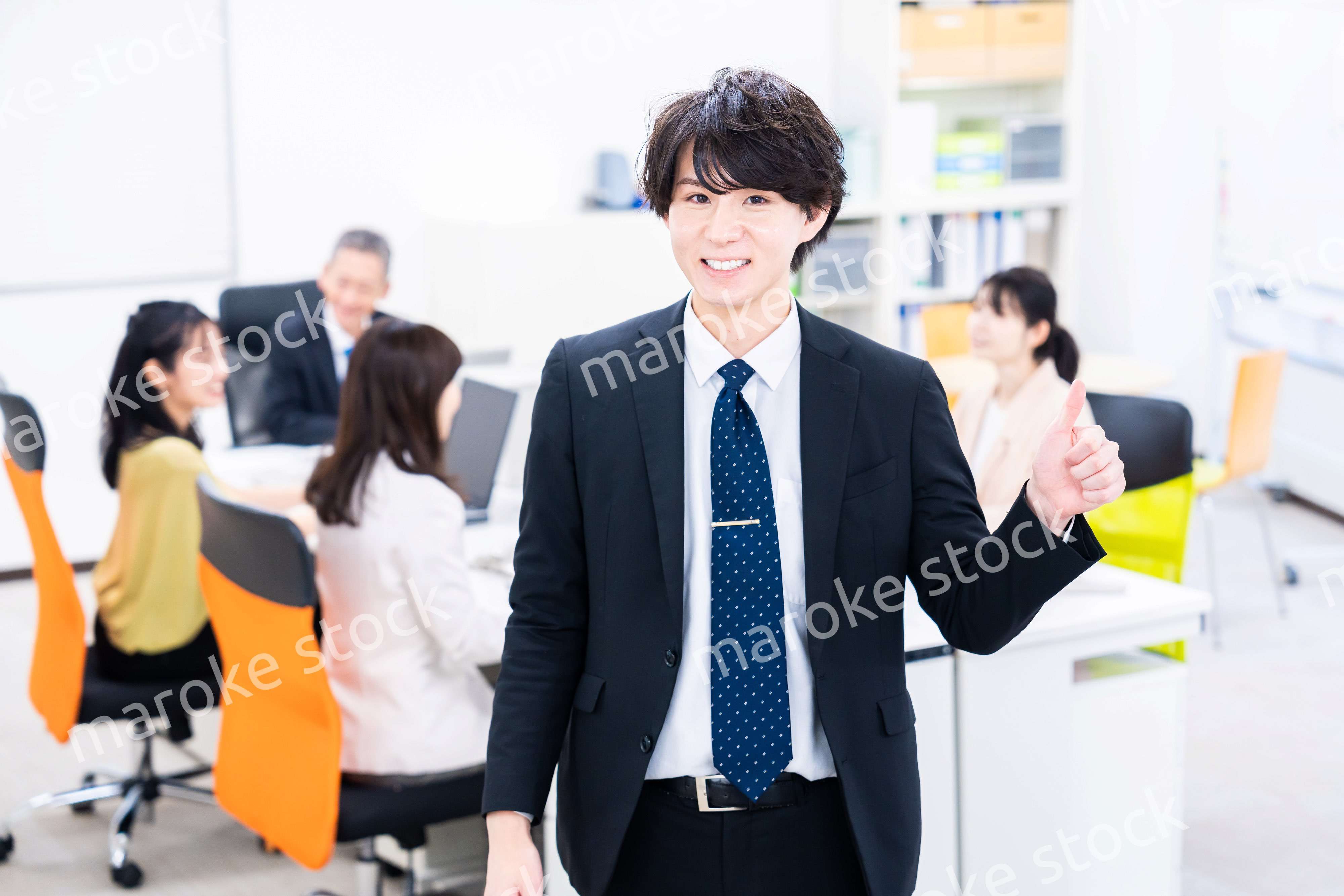 笑顔でグッドサインをする若いビジネスマン