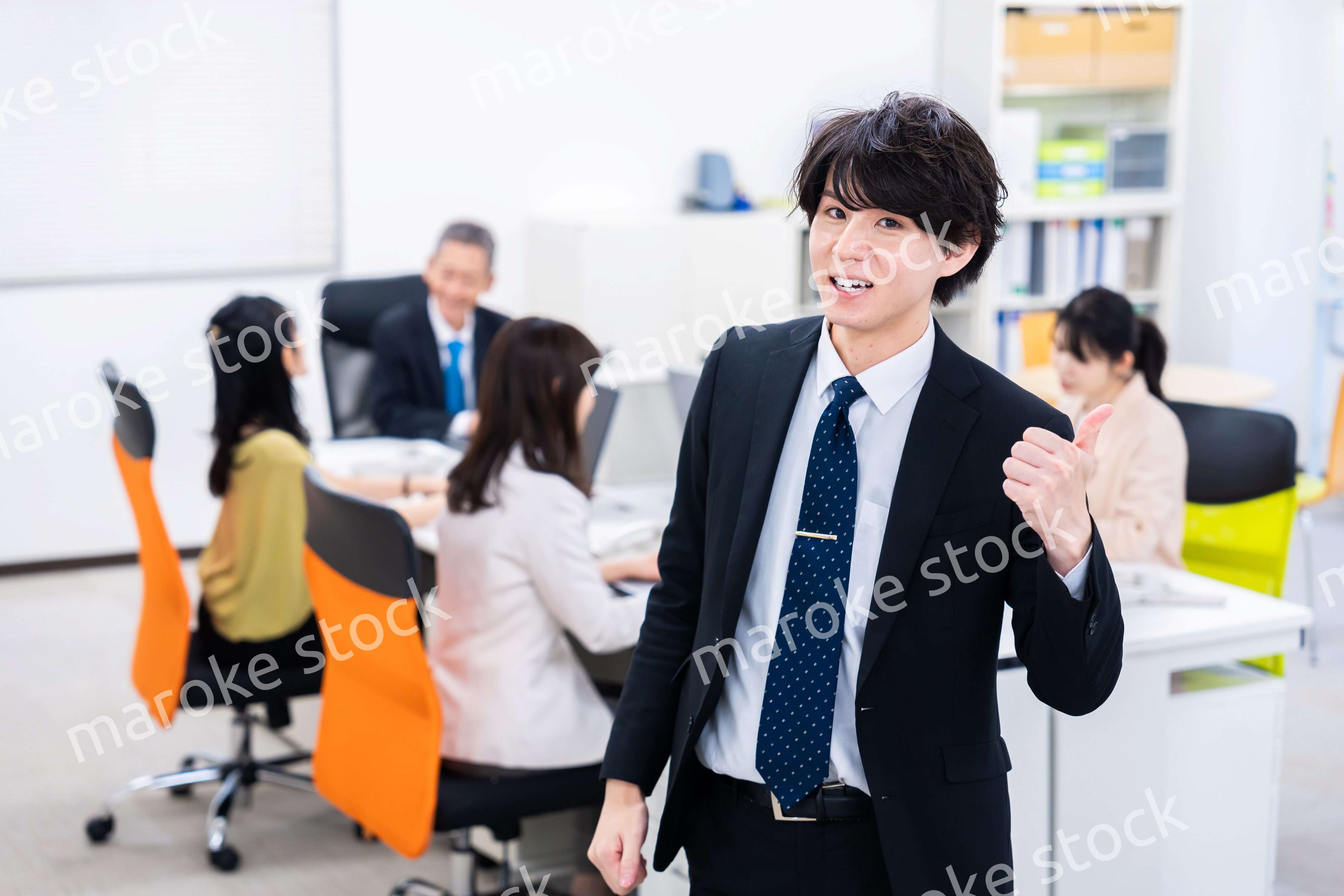 笑顔でグッドサインをする若いビジネスマン