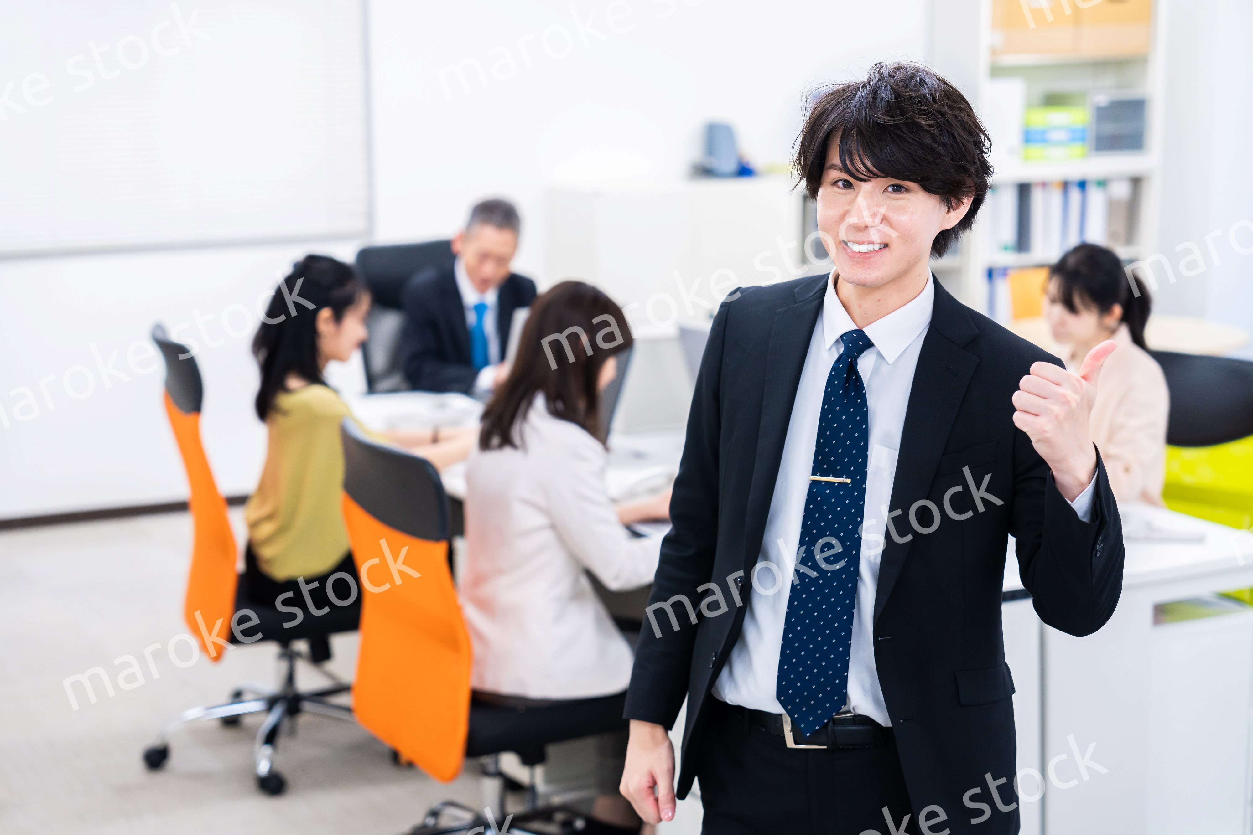 笑顔でグッドサインをする若いビジネスマン