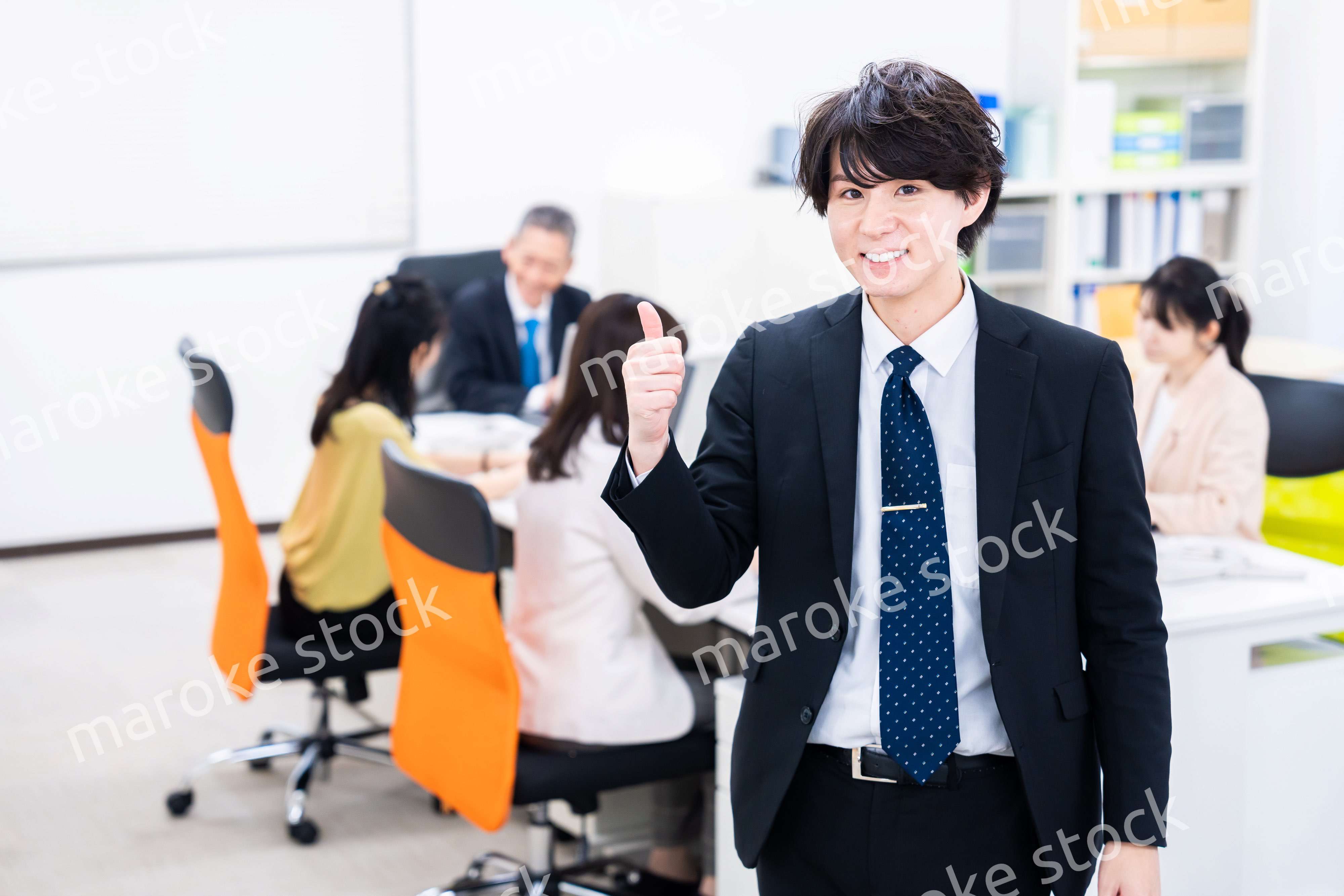 笑顔でグッドサインをする若いビジネスマン