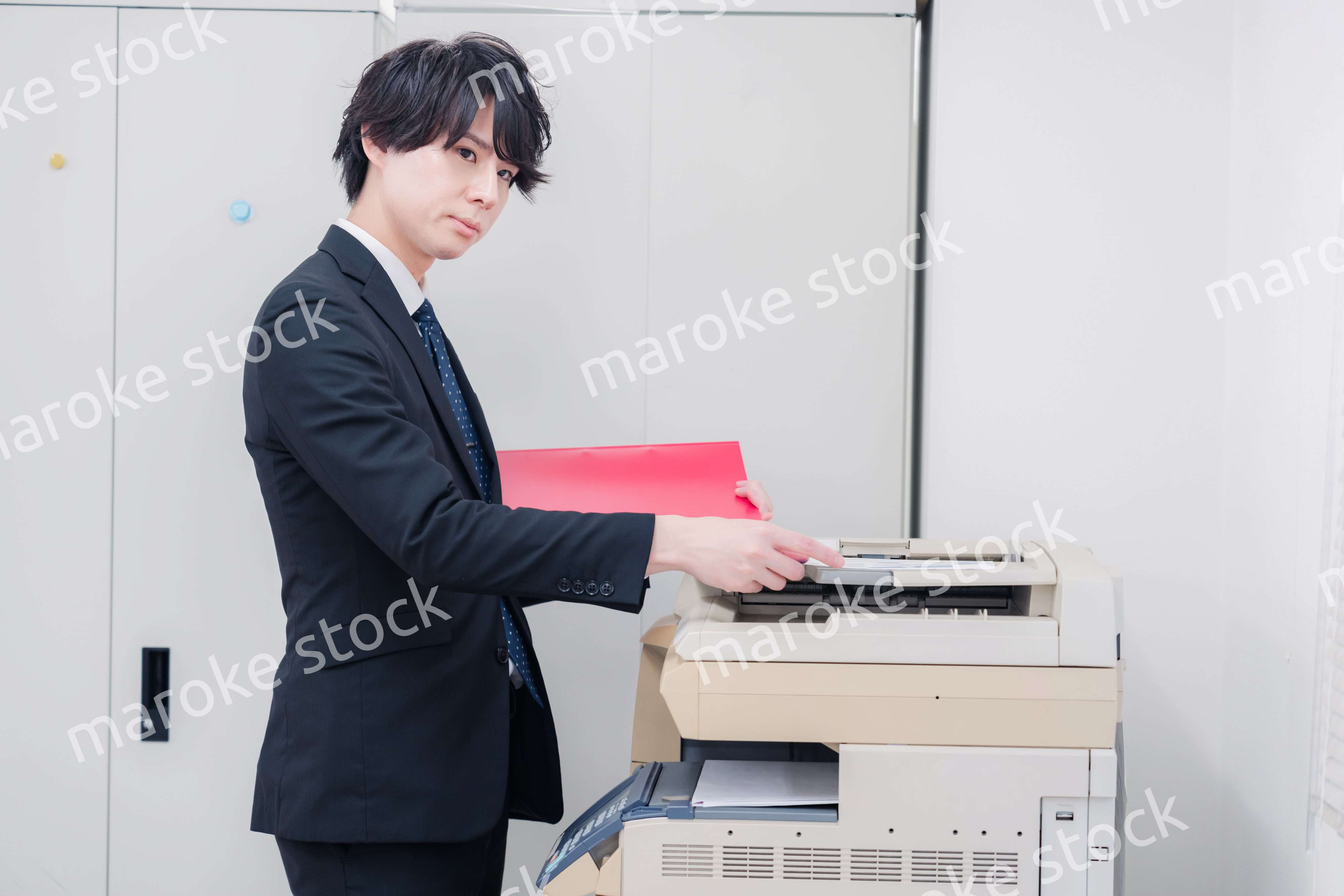 オフィスでコピーを取るスーツを着た男性