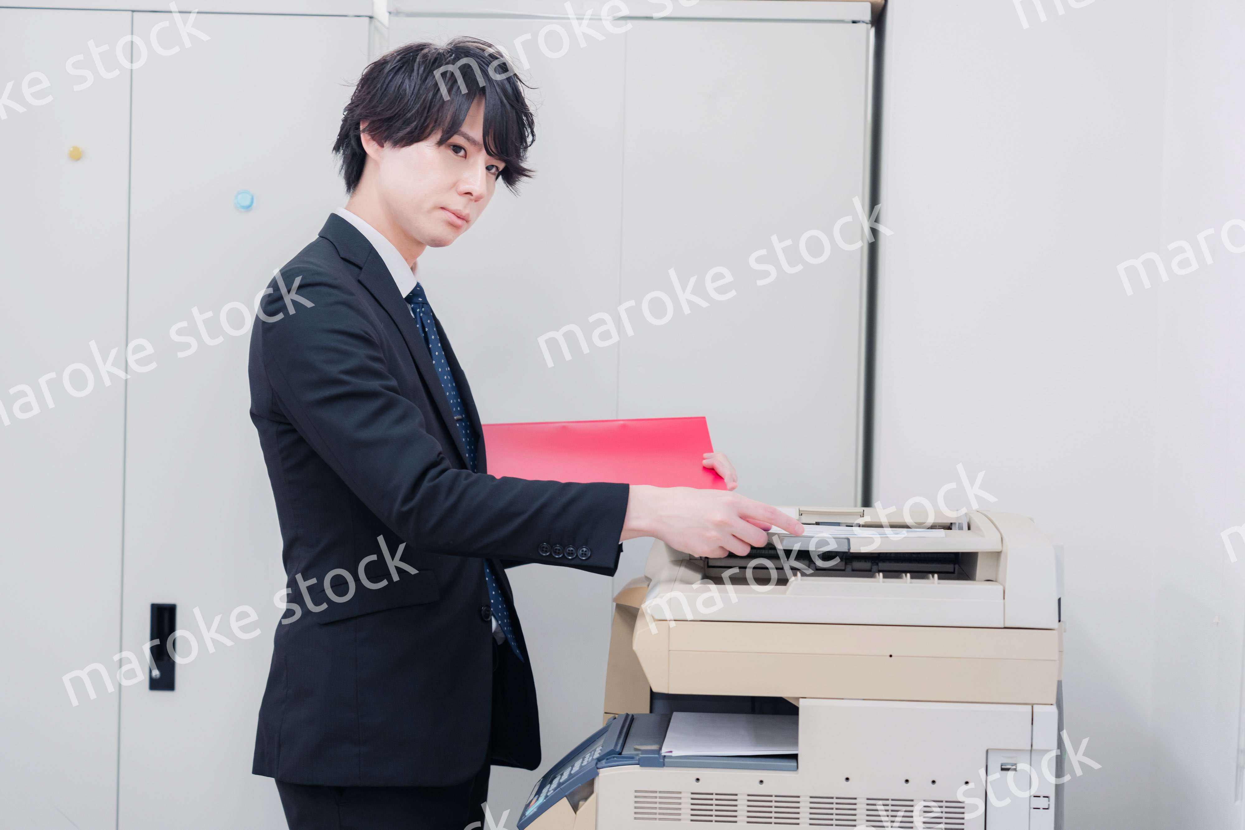 オフィスでコピーを取るスーツを着た男性