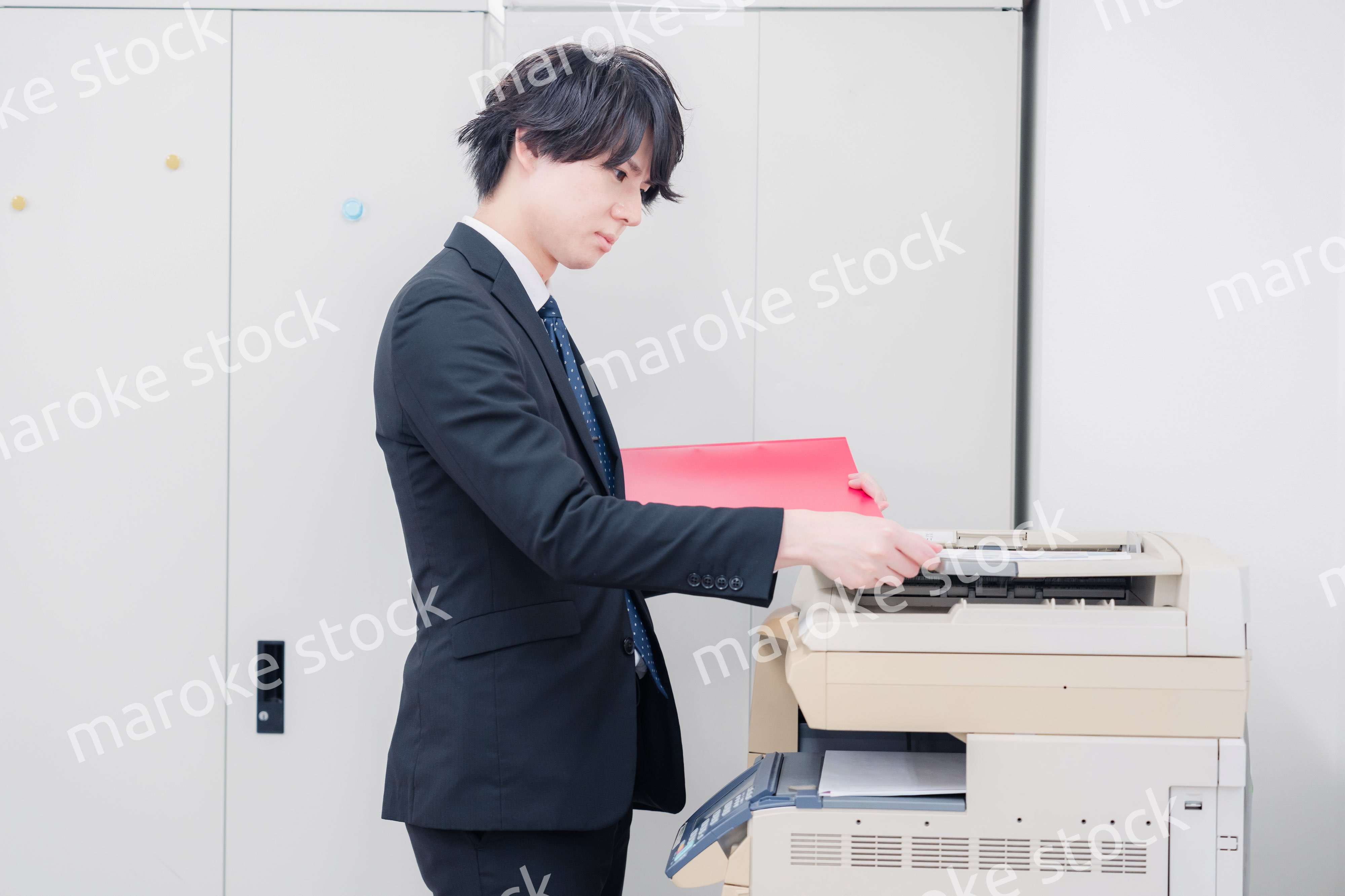 オフィスでコピーを取るスーツを着た男性
