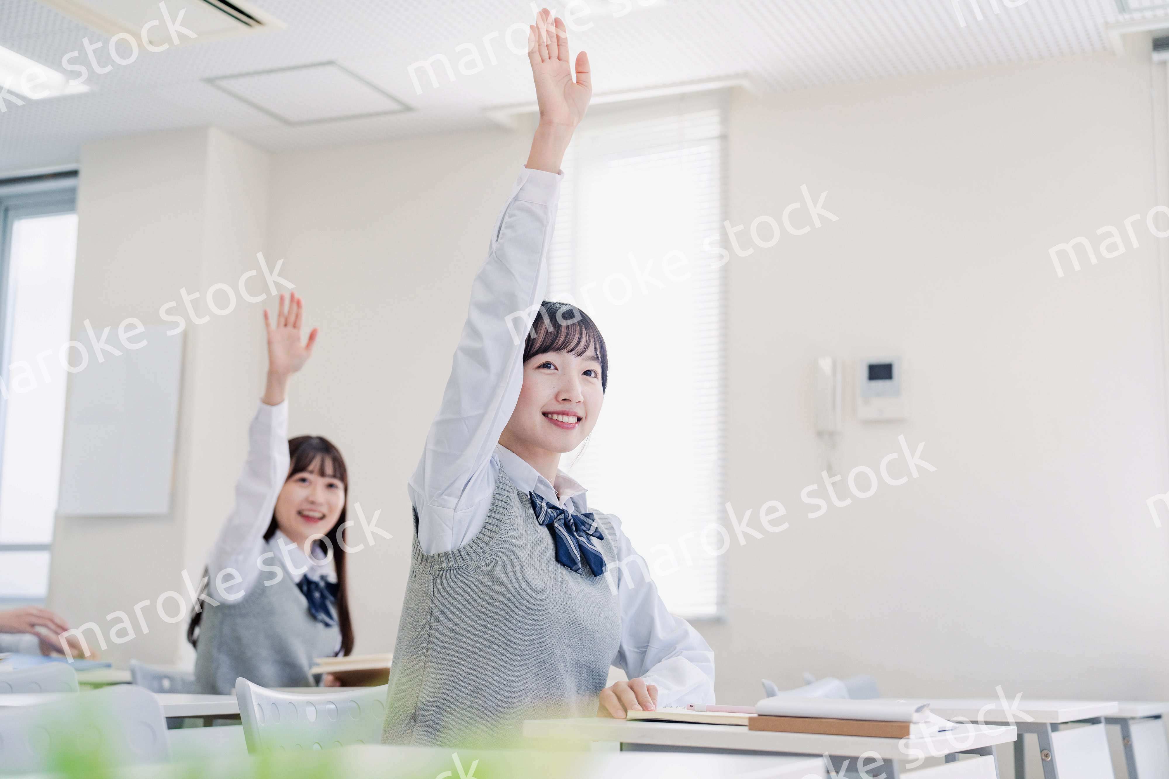 手を上げて発表をする女子高生