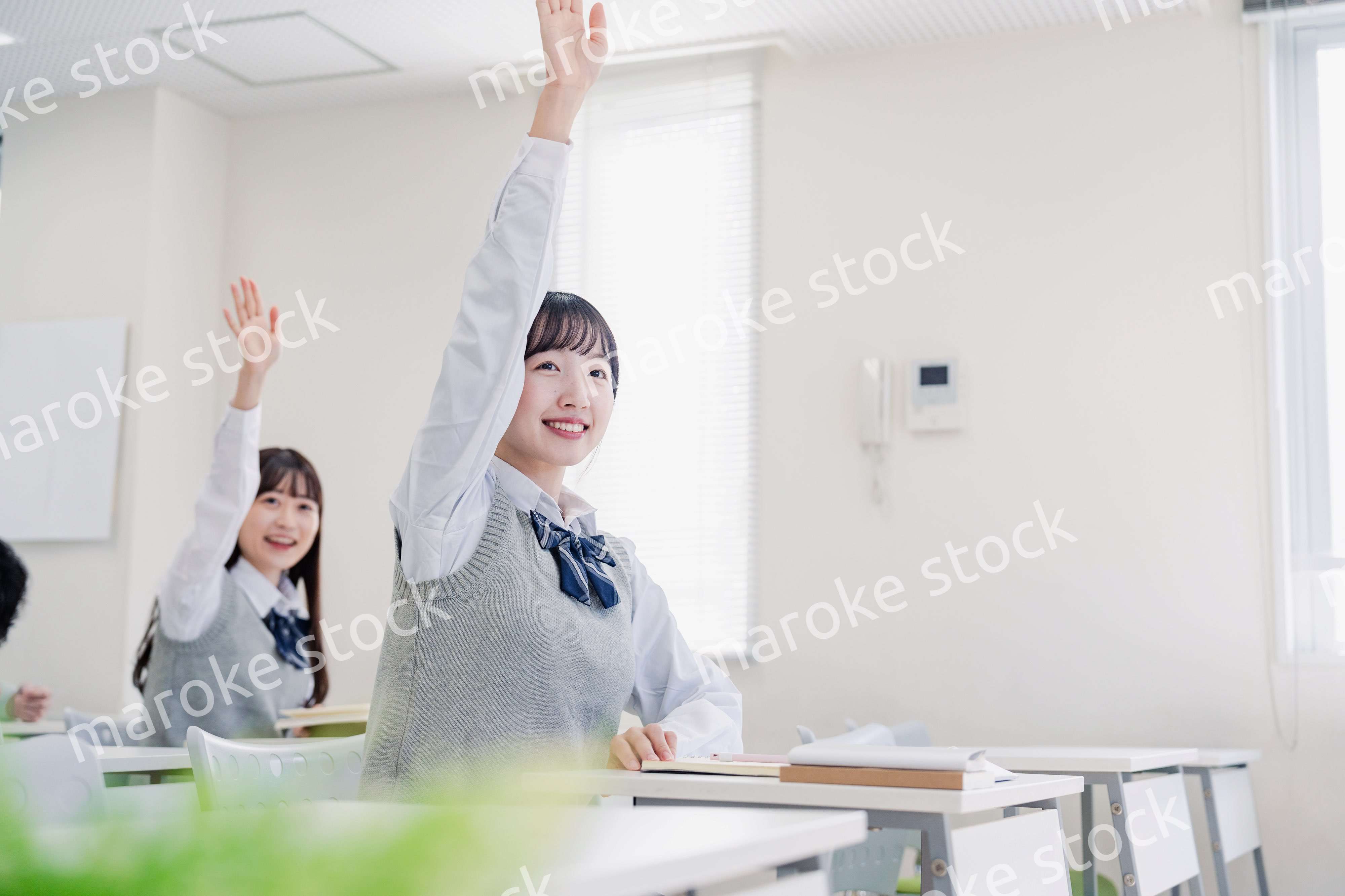 手を上げて発表をする女子高生