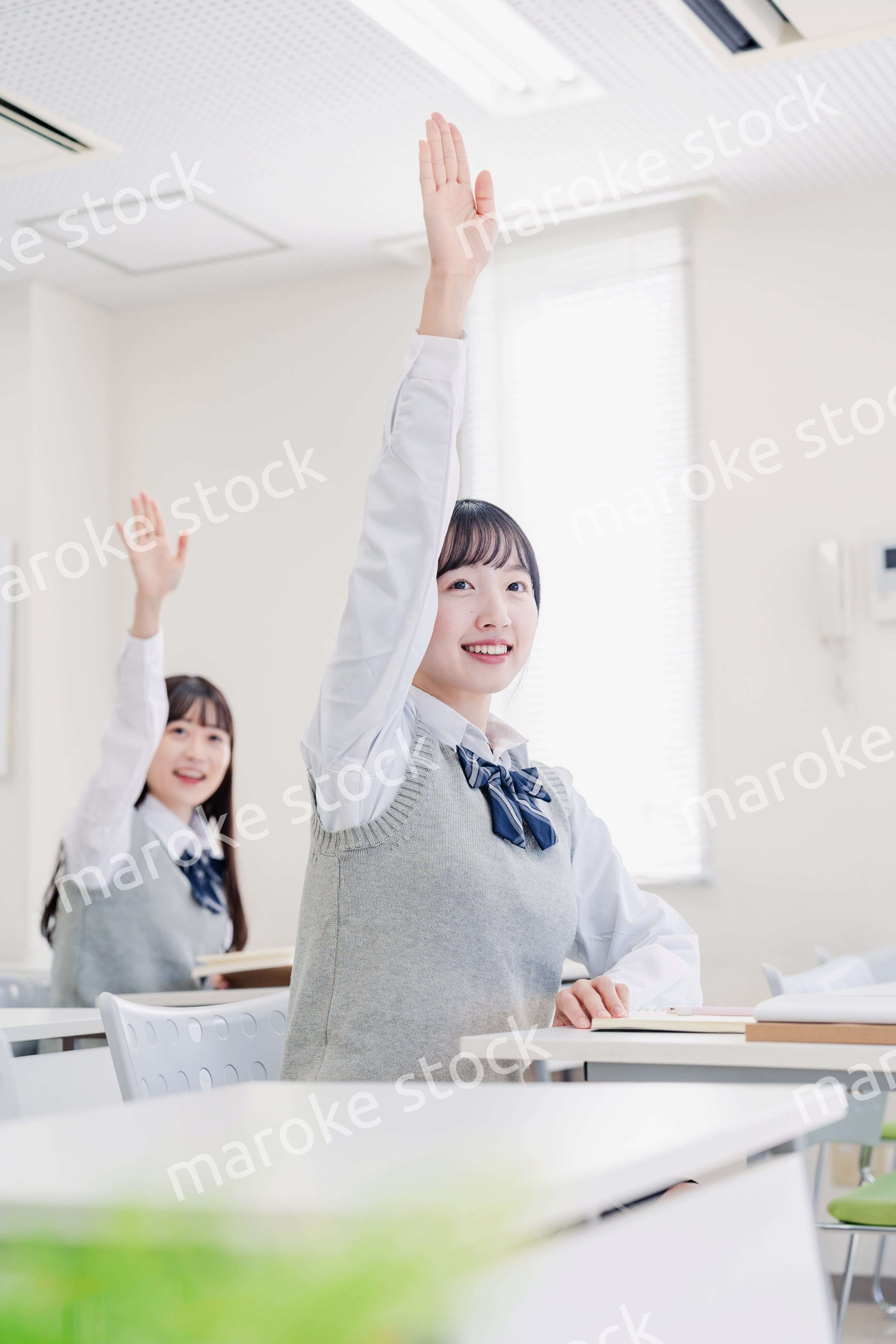 手を上げて発表をする女子高生