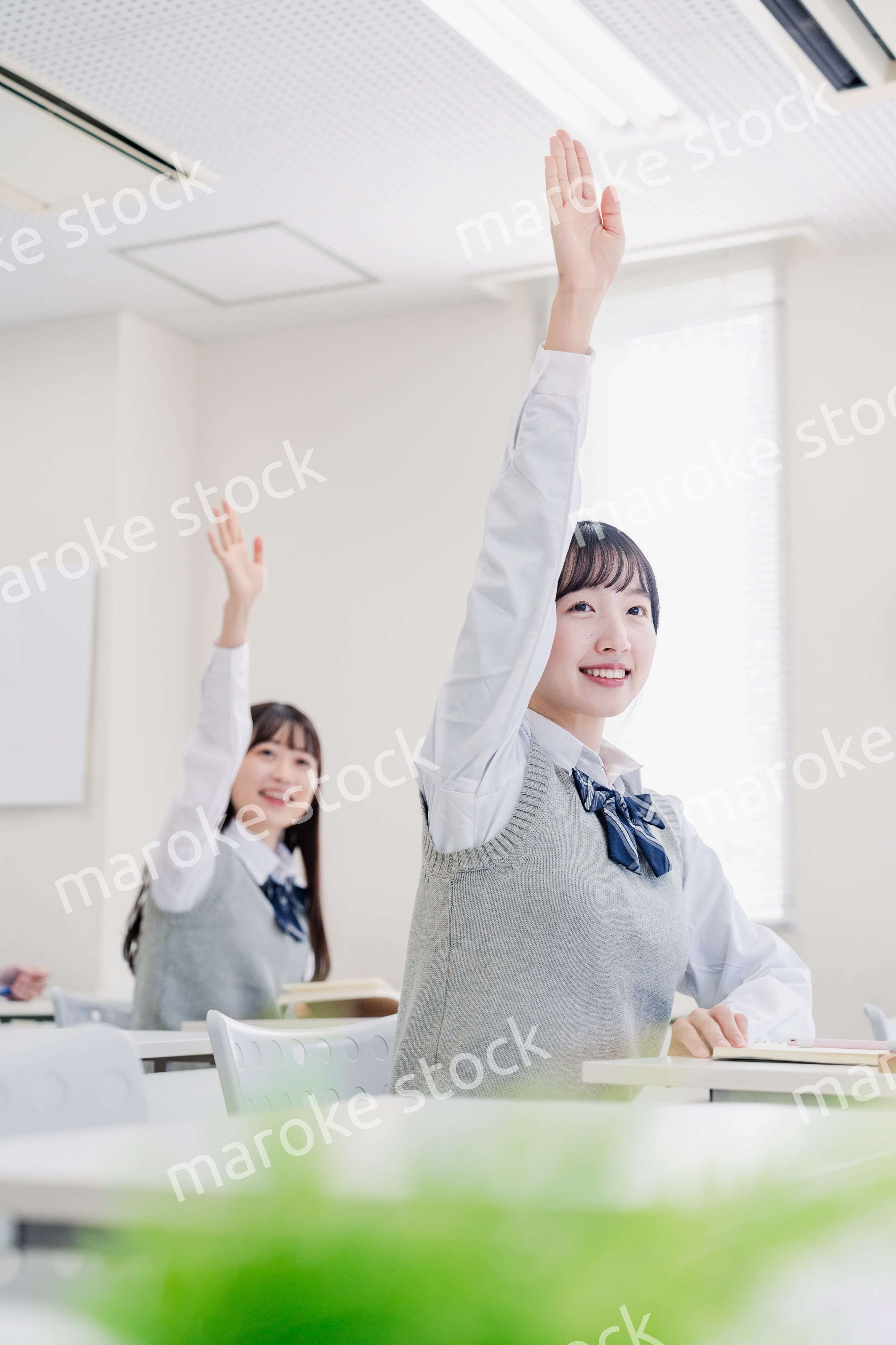 手を上げて発表をする女子高生