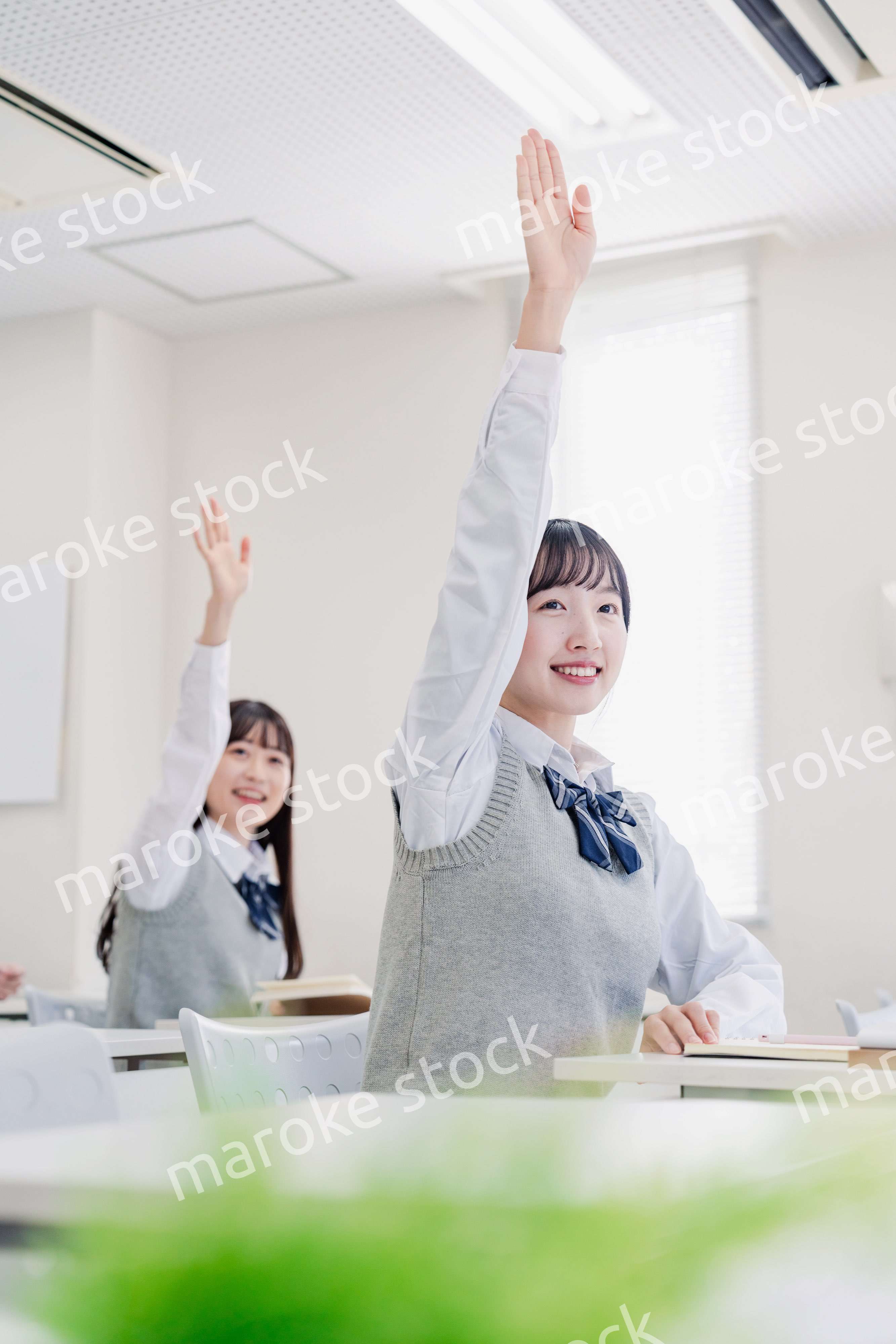 手を上げて発表をする女子高生