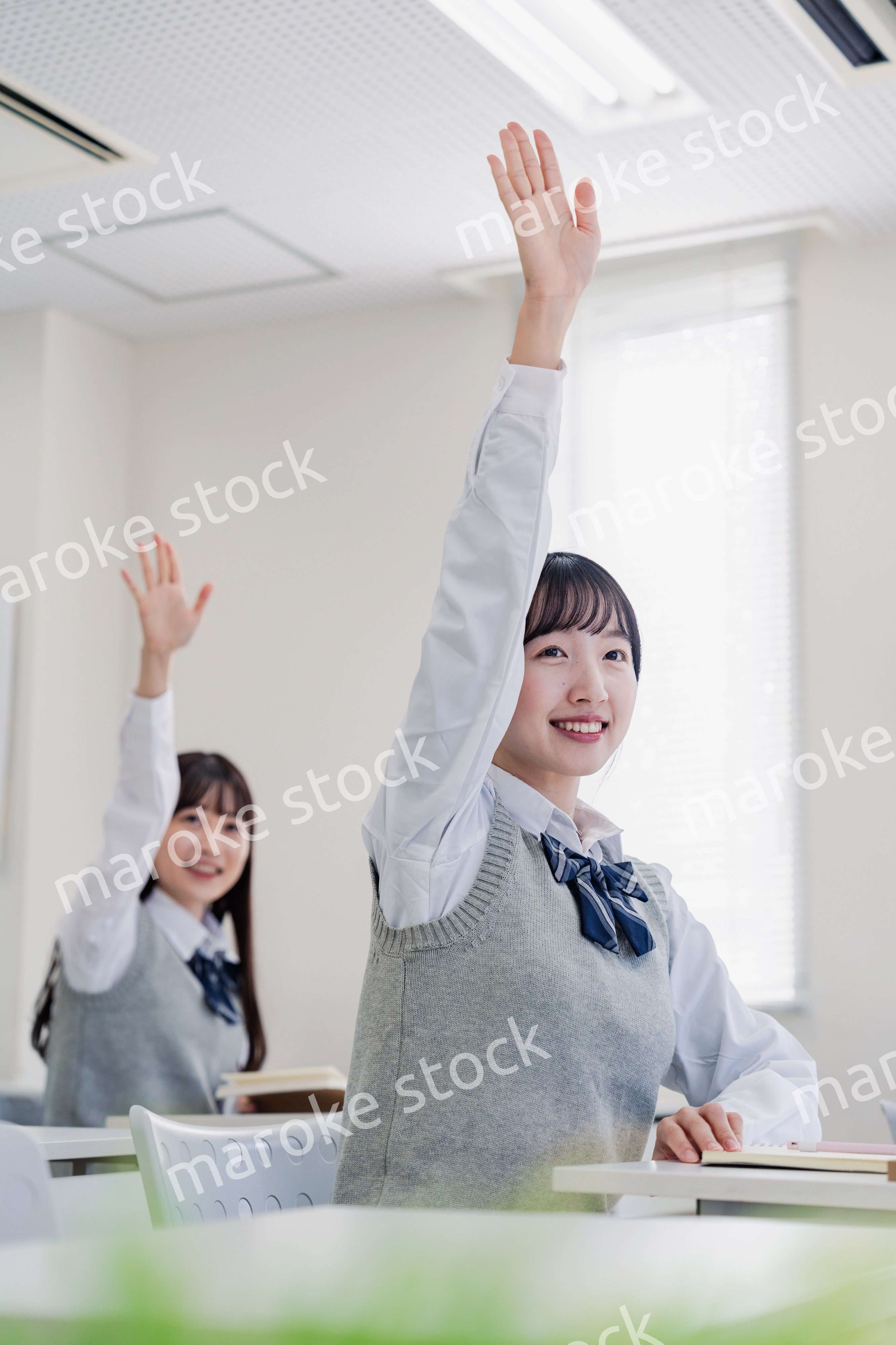 手を上げて発表をする女子高生